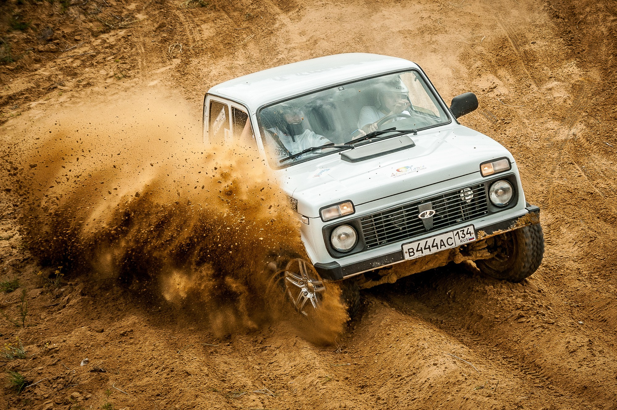 Белая Нива во время гонки входит в поворот, поднимая пыль