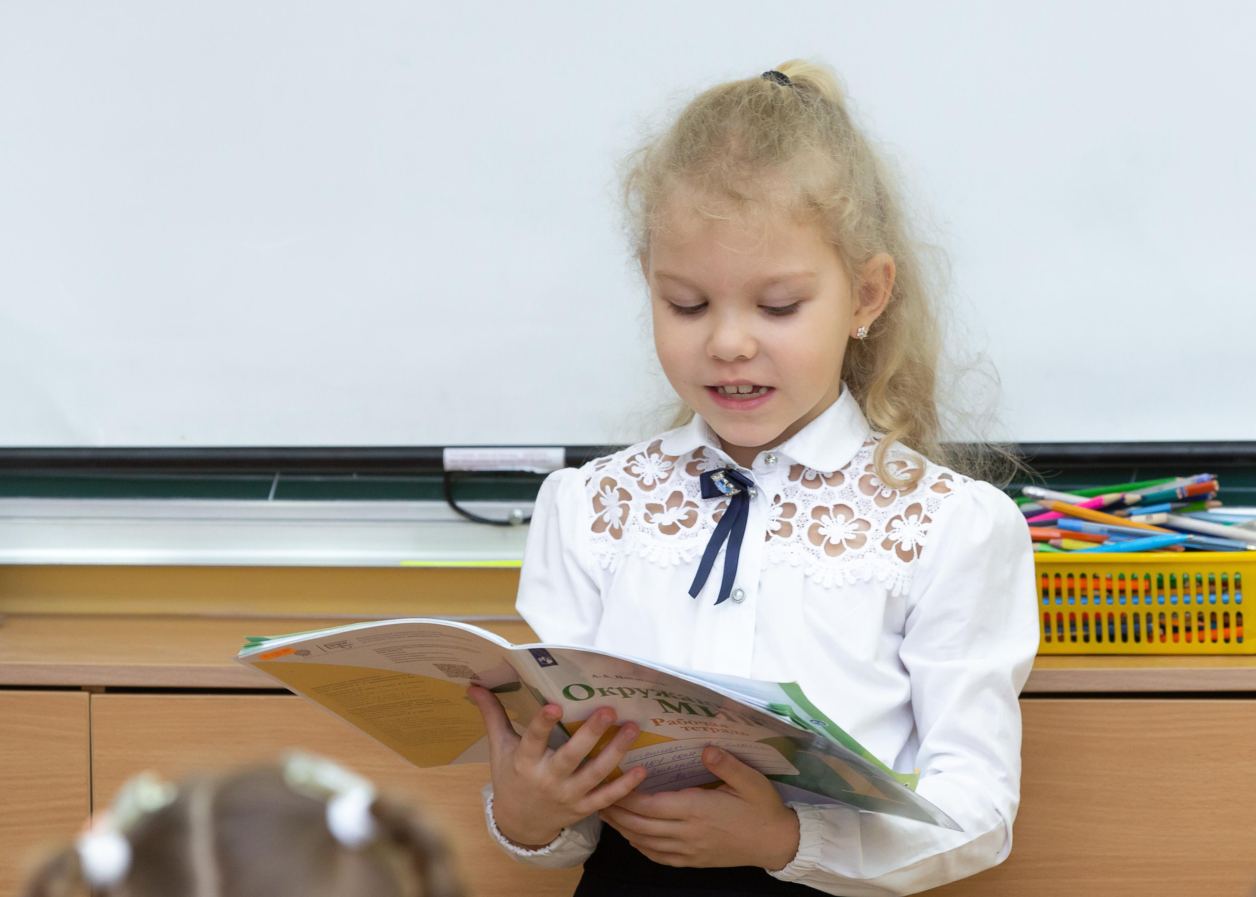 девочка читает учебник у доски