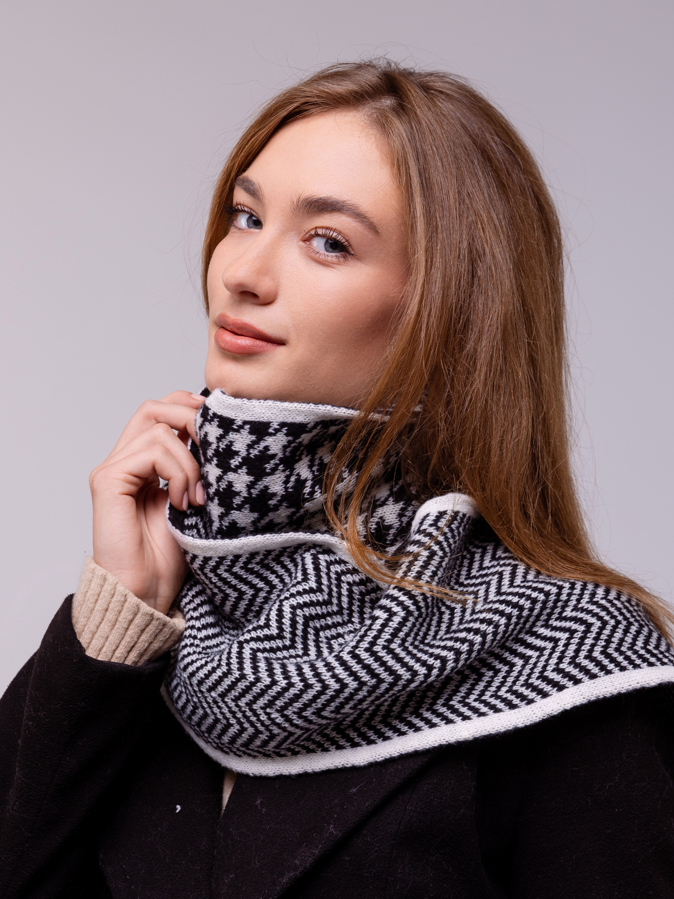 На шее девушки шарф в черно белой гамме наполовину крупный рисунок, другая половина мелкий рисунок.