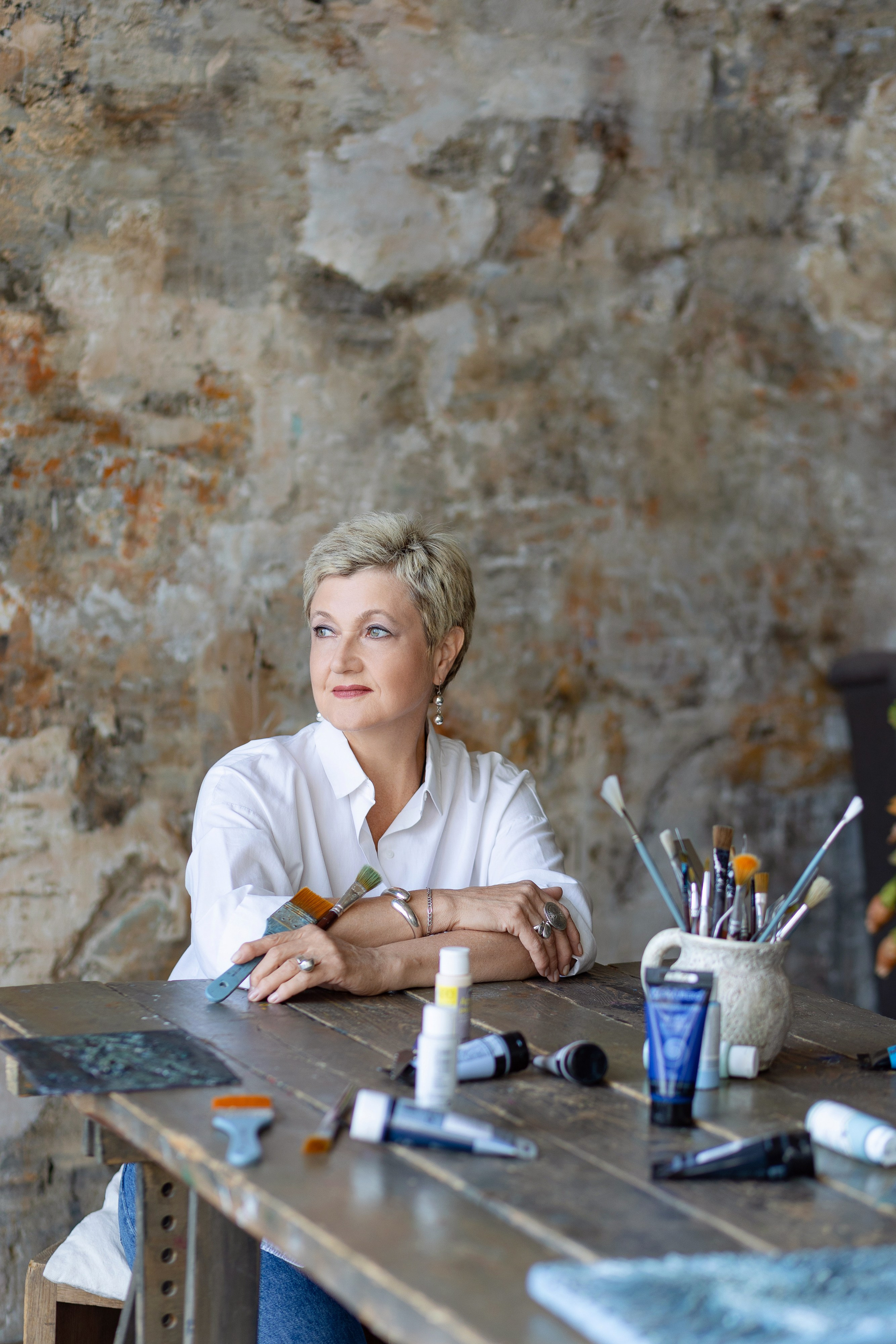 Художница сидит за столом, сложив руки на стол.