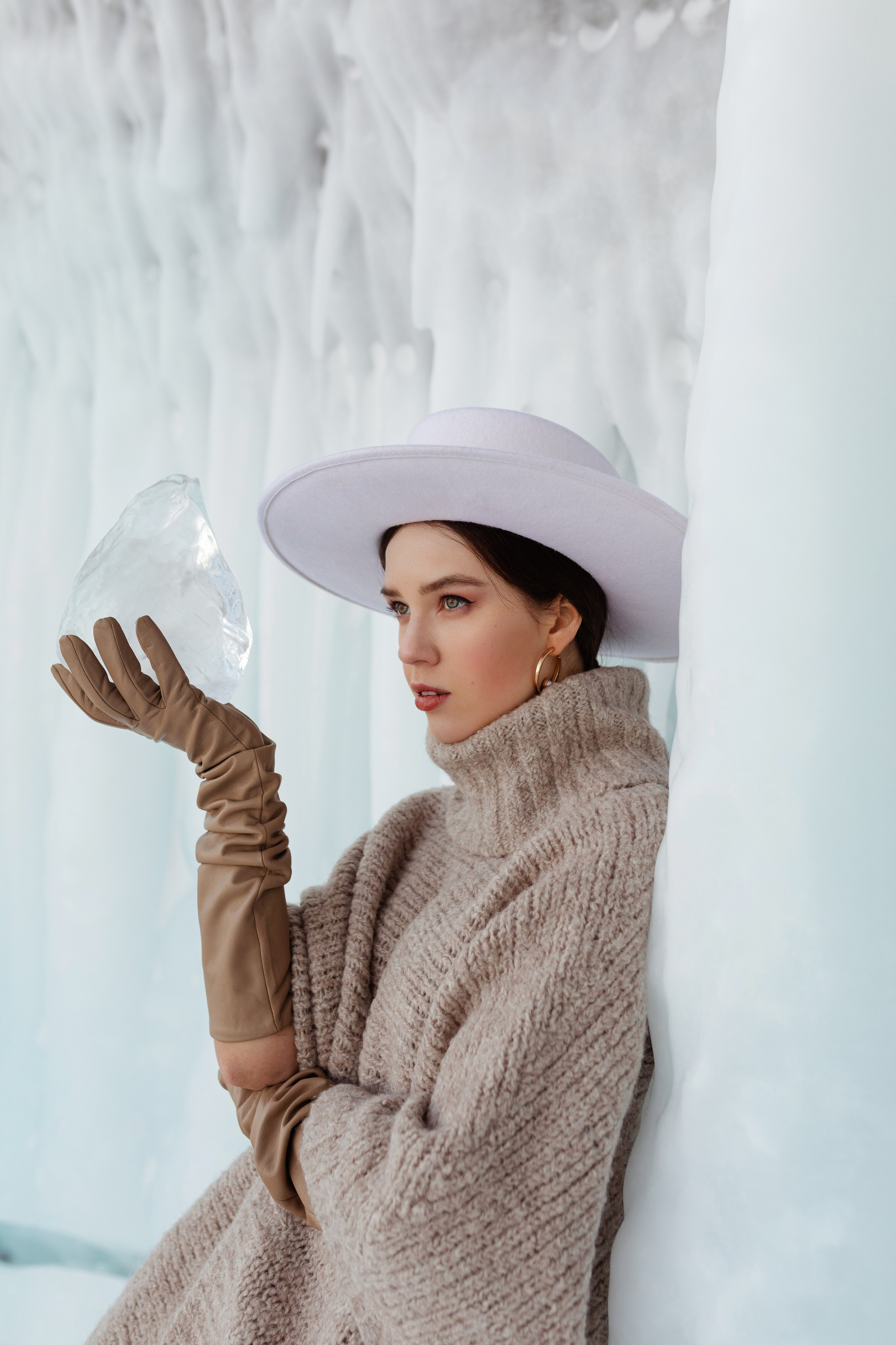 Девушка в стильной одежде среди льдов держит в руках большую льдину