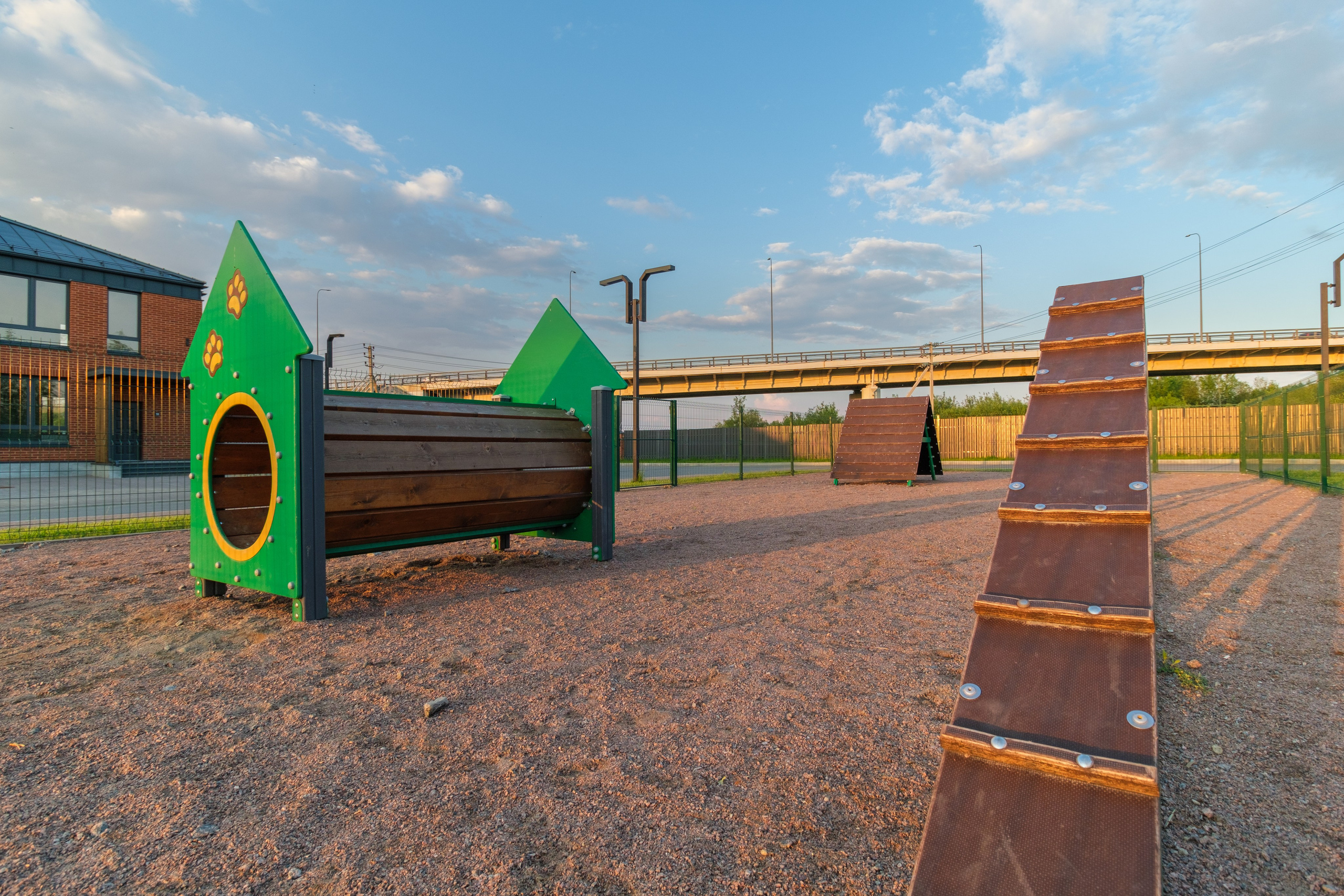 Площадка для выгула и дрессировки собак, расположенная недалеко от коттеджей из красного кирпича.