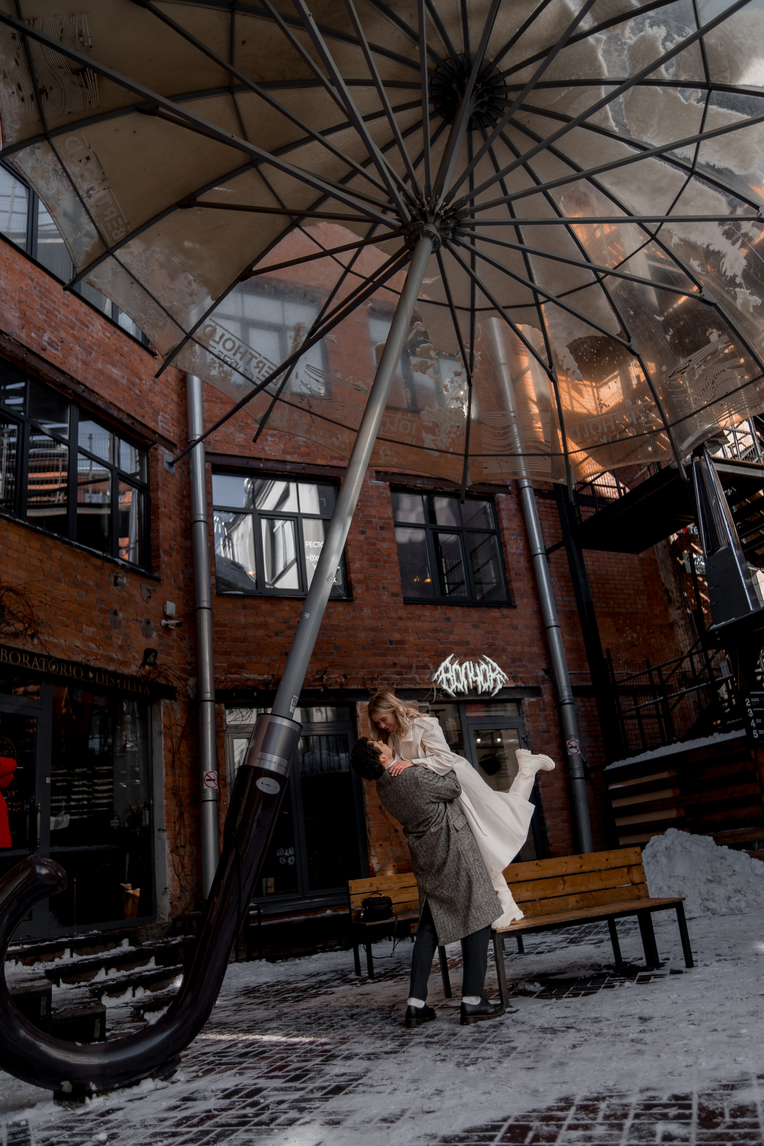 Молодой человек и девушка в пальто обнимаются в Бергольдц центре в Санкт-Петербурге.