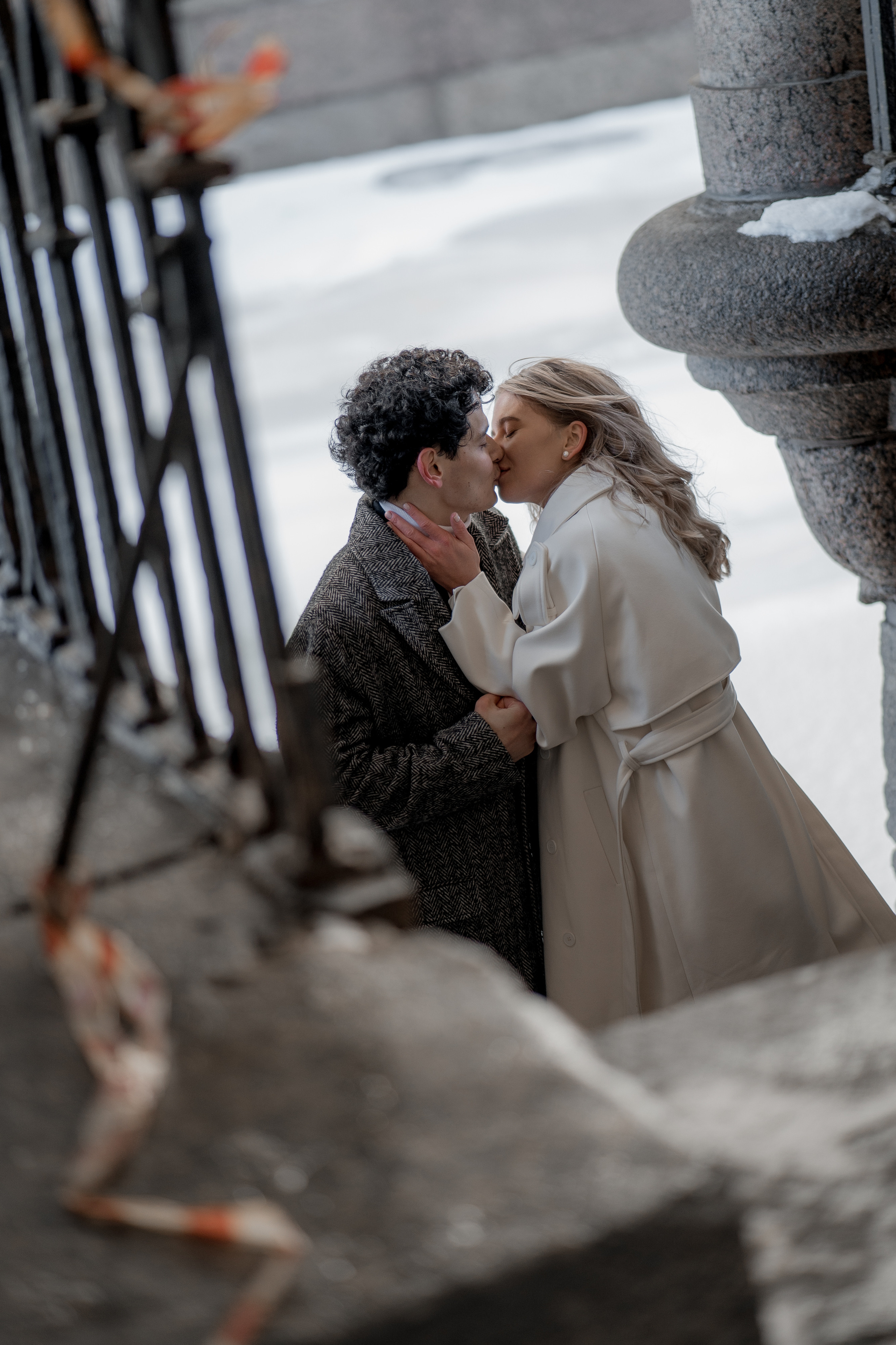 Влюбленная пара в пальто целуется на Зимней канавке зимой в Санкт-Петербурге