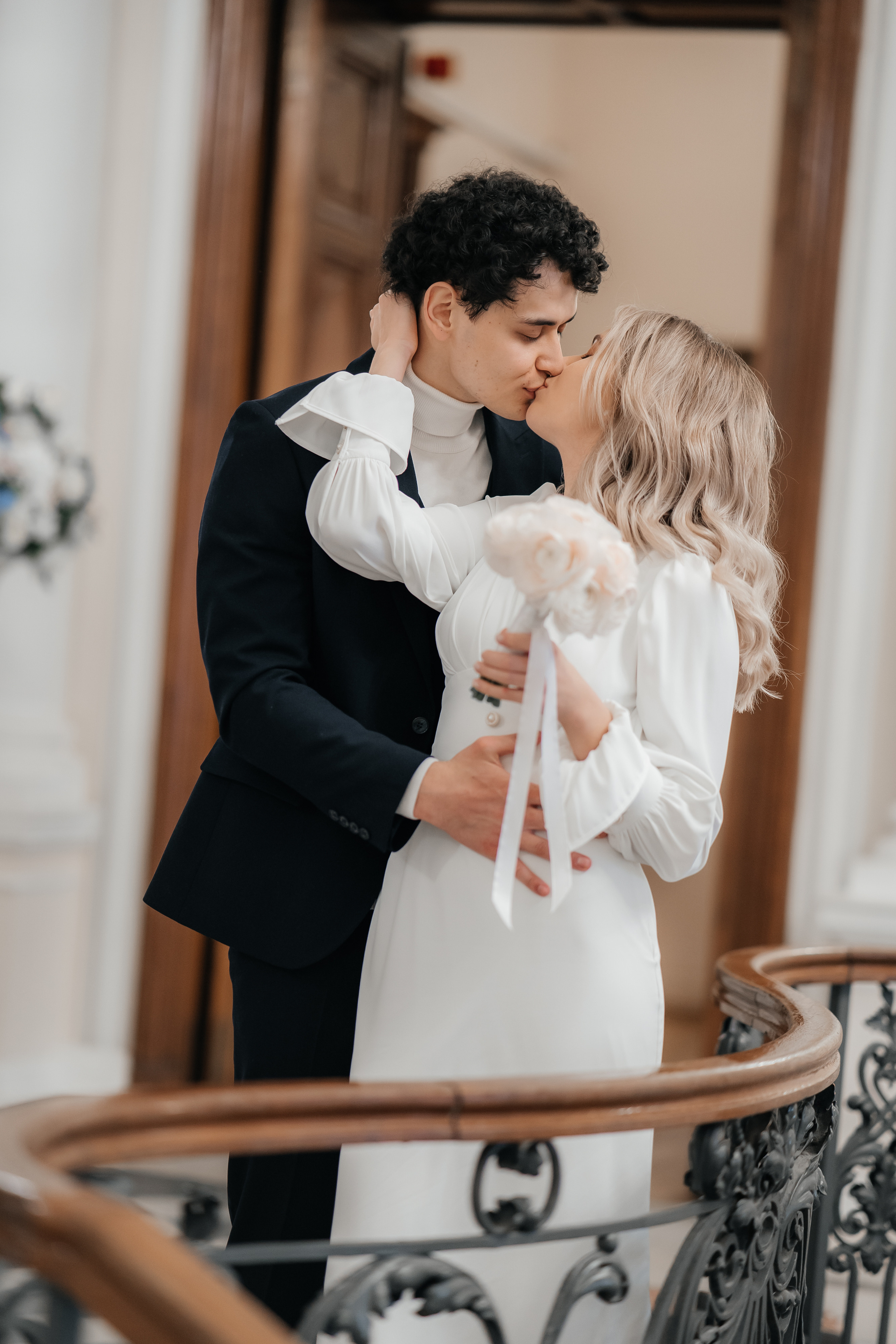 Жених и невеста целуются на лестнице дворца бракосочетания №2