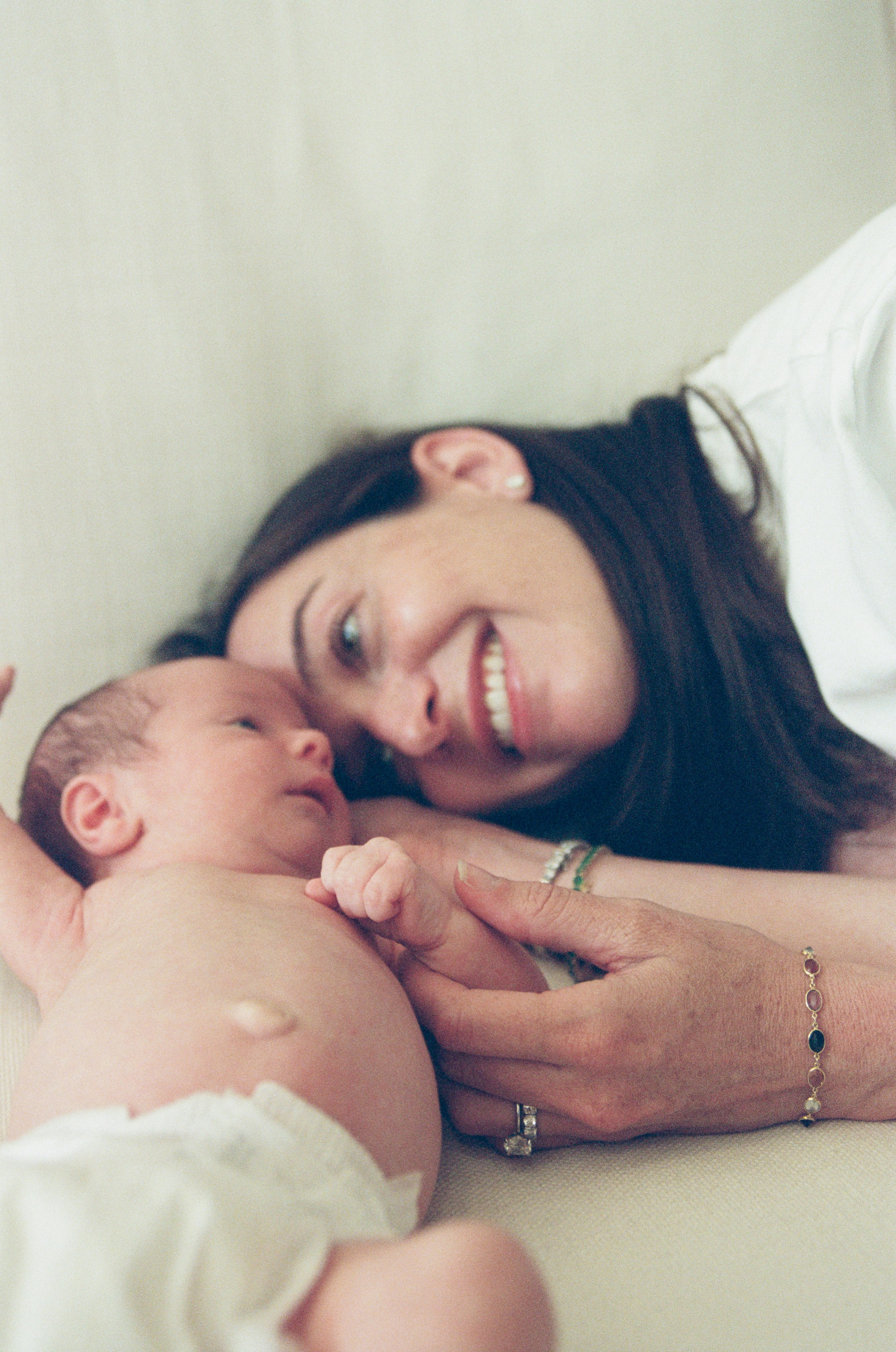Mother leaning down to the couch to her baby in a diaper with a bright smile on her face