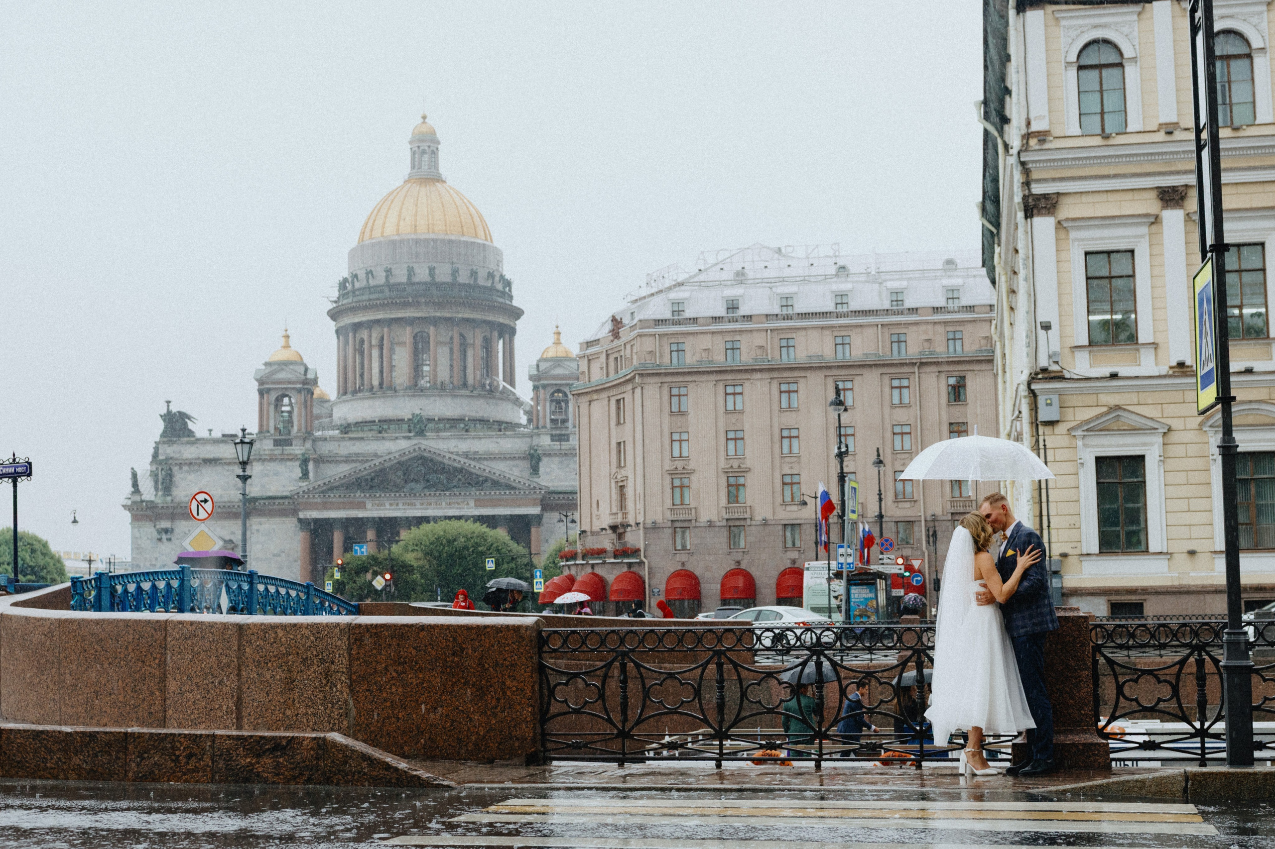 Свадебная фотосессия под дождем у Исаакиевского собора в Санкт-Петербурге: жених и невеста стоят под зонтом. Романтическая съемка в дождливую погоду в центре СПб.