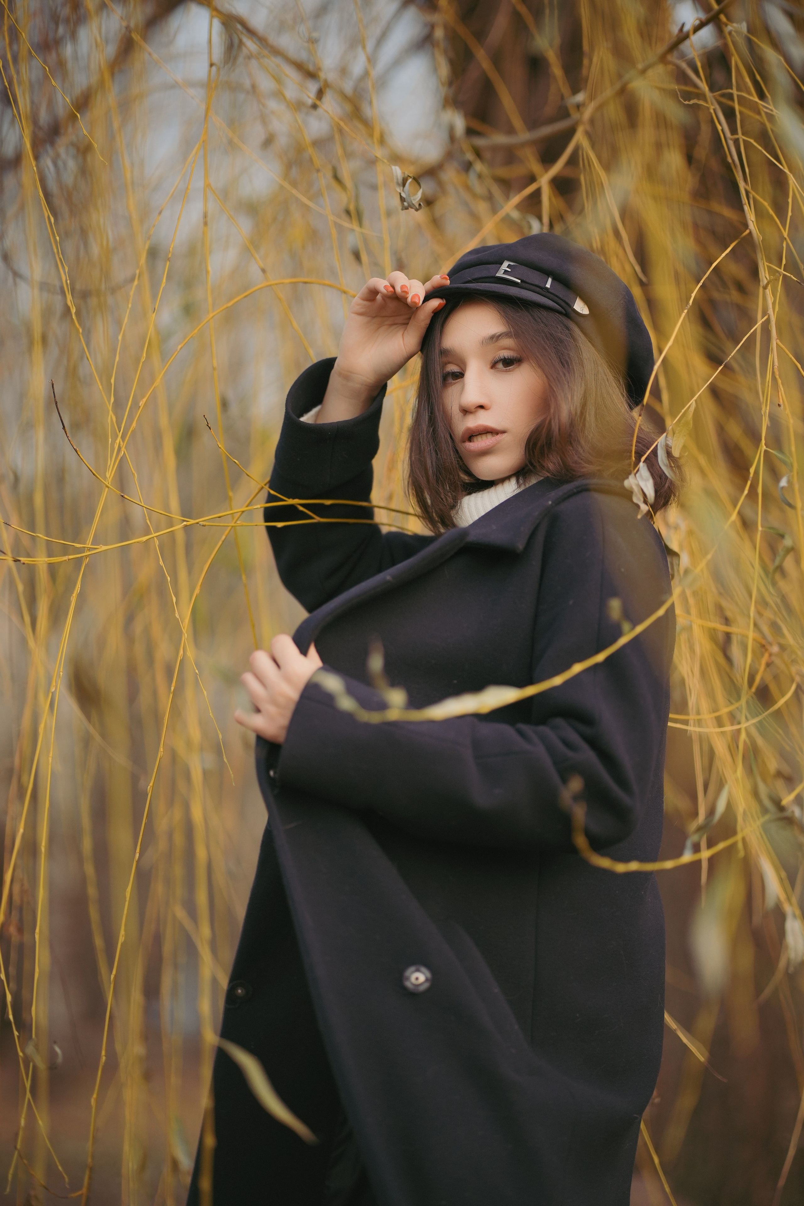 молодая прекрасная девушка гуляет по осеннему парку в темном пальто и в кепке