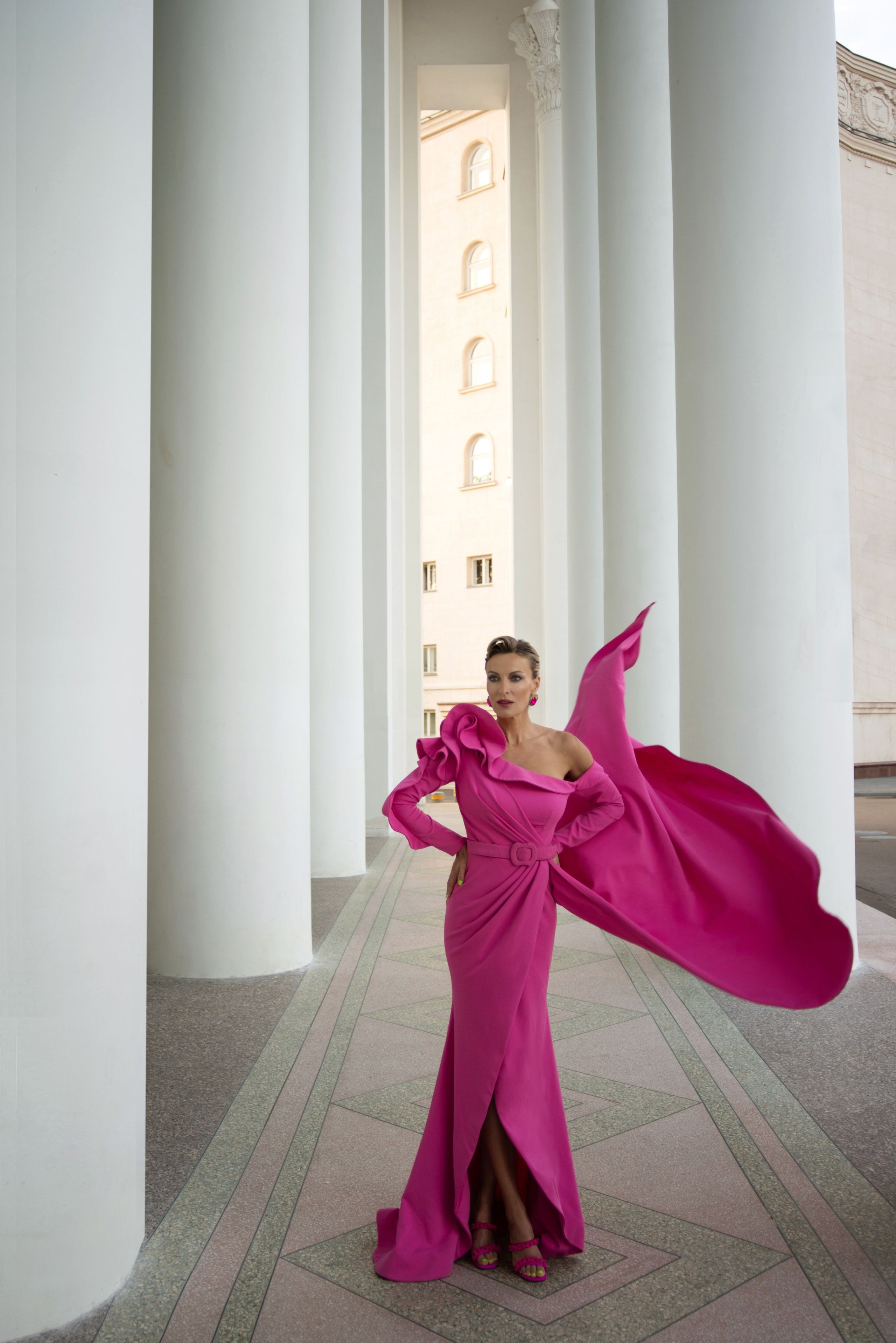 Уличная фотосессия среди белых колонн в развевающемся платье