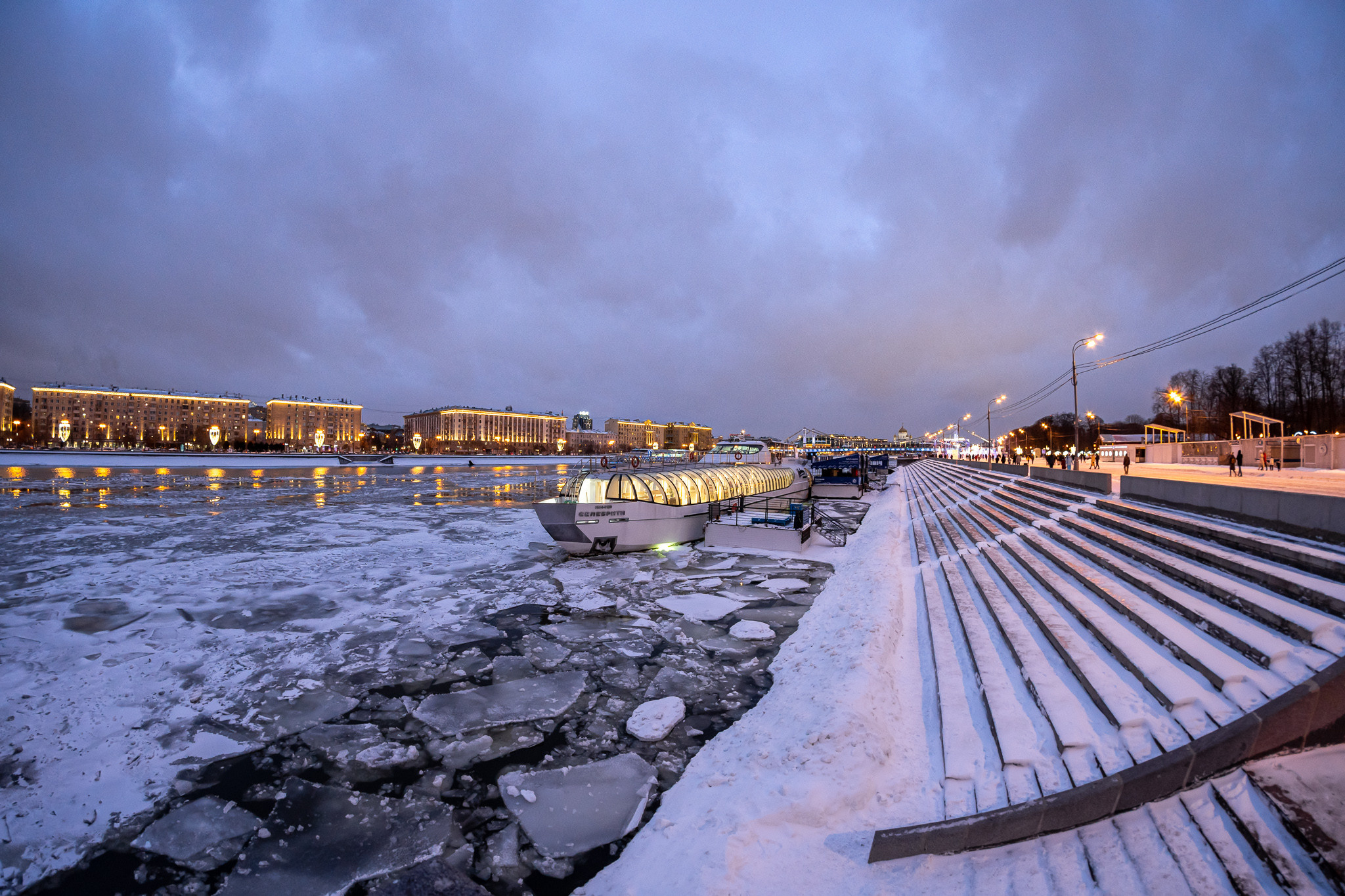 Парк Горького зимой на набережной с видом на реку во льду и прогулочную яхту