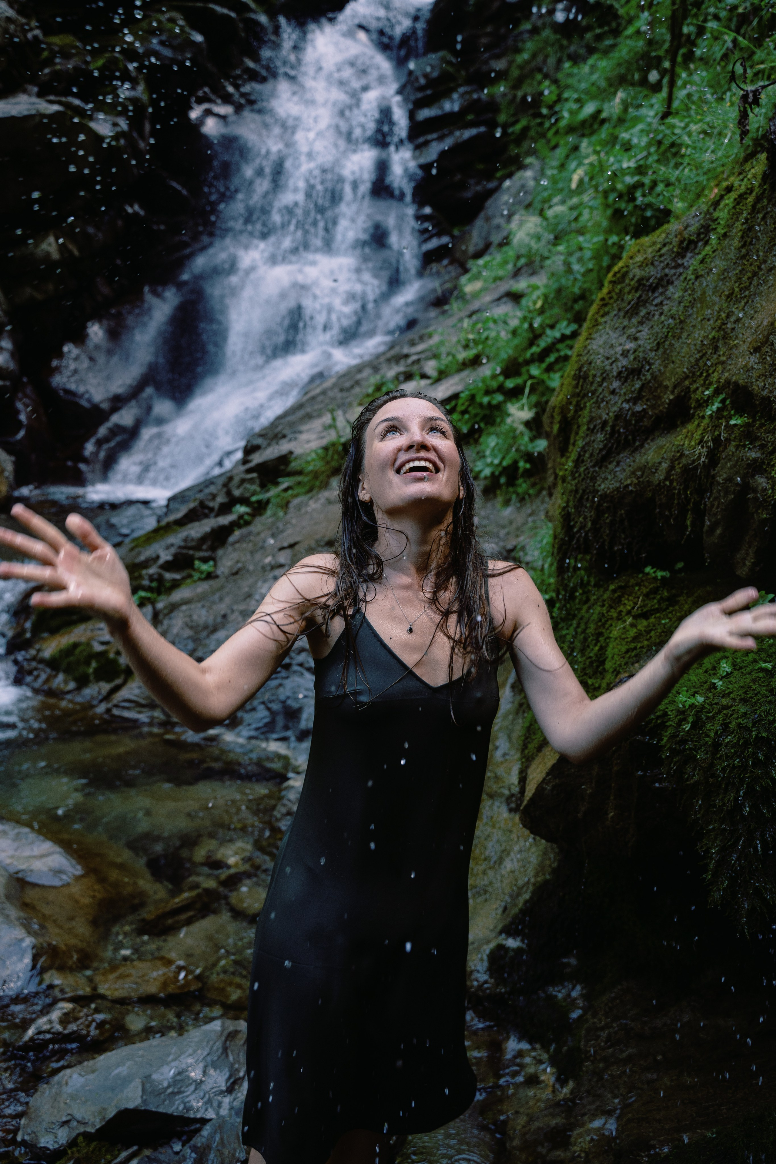 Снимок девушки на фоне водопада и с брызгами воды 