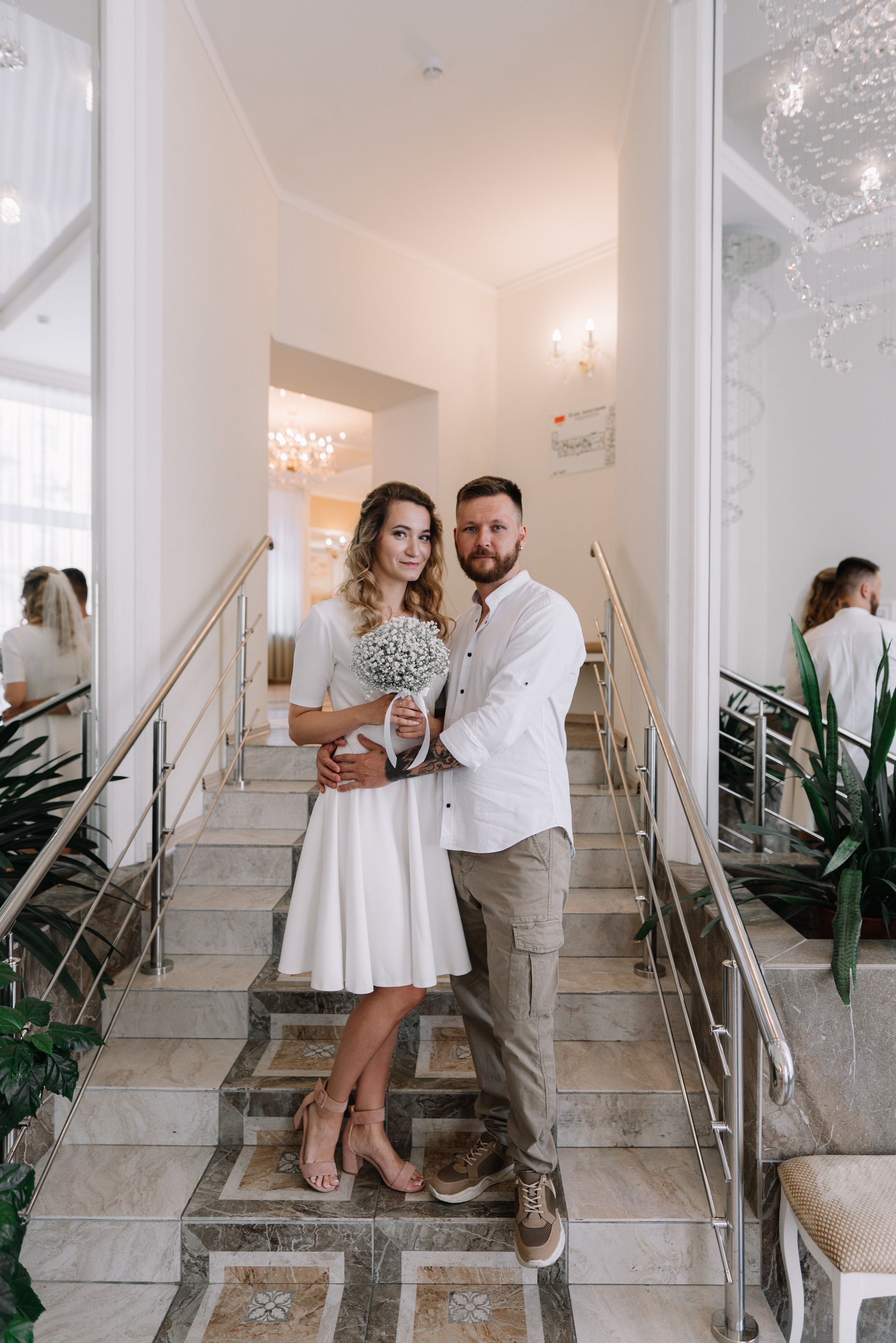 жених и невеста позируют на лестнице в загсе московского района