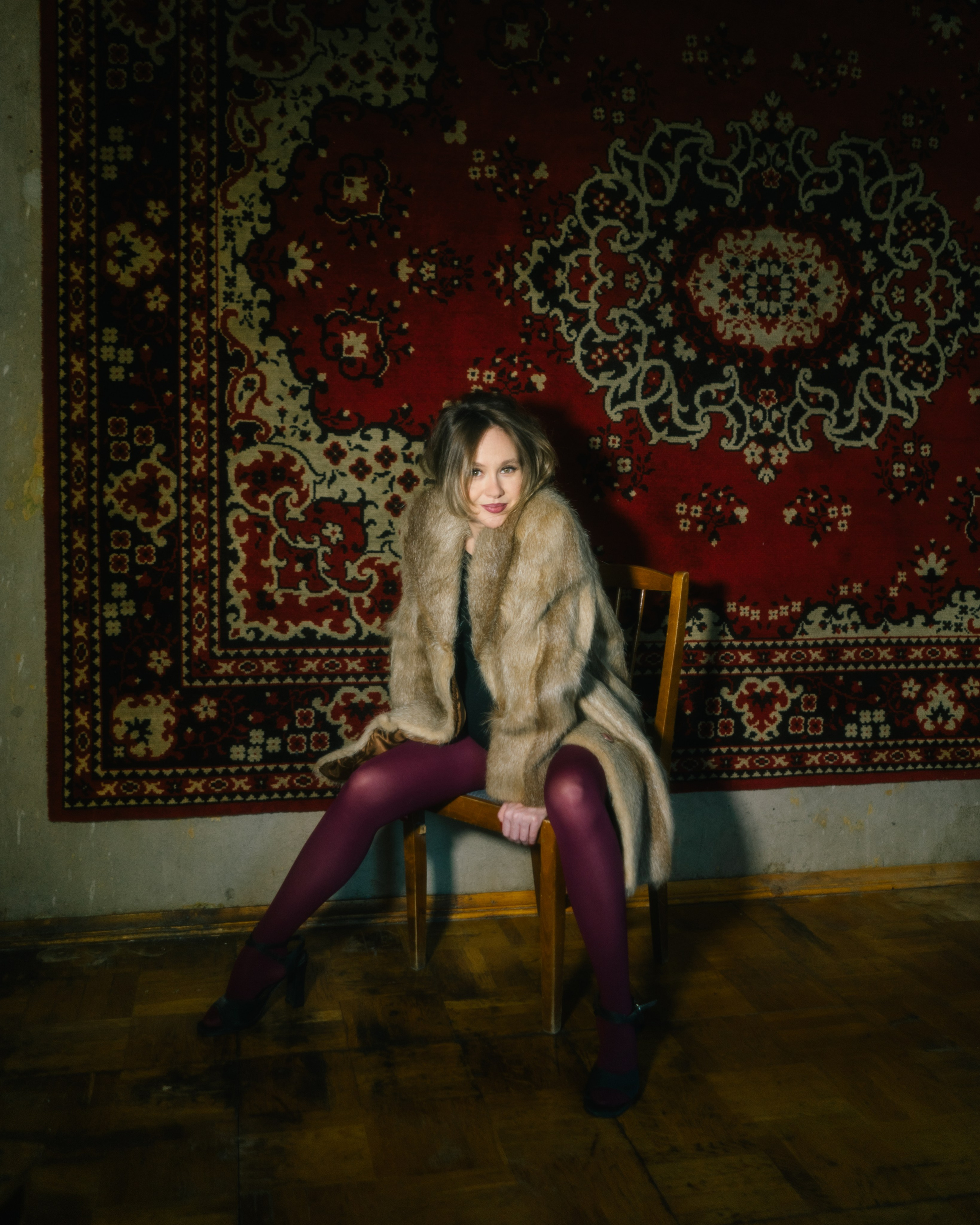 Беременная в шубе на стуле у винтажного ковра — выразительная студийная фотосессия беременности в Санкт-Петербурге в стиле девяностых. 