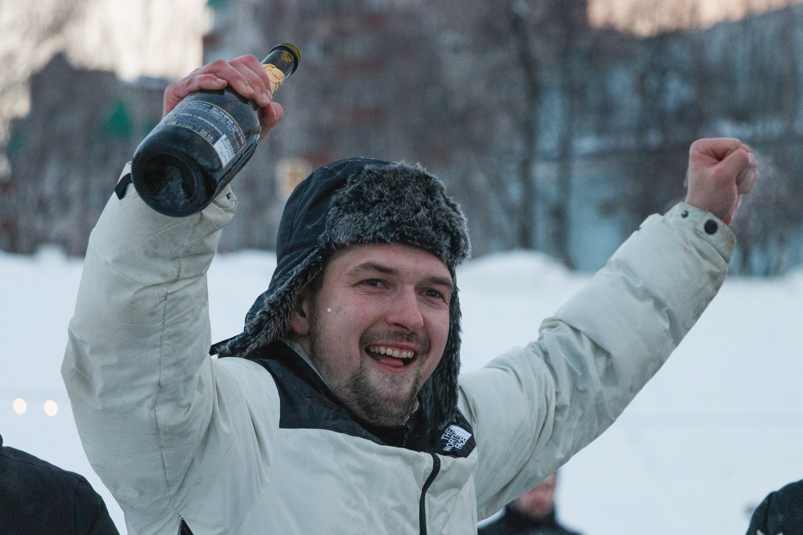 Болельщик радуется победе гонщика, активно размахивая бутылкой шампанского