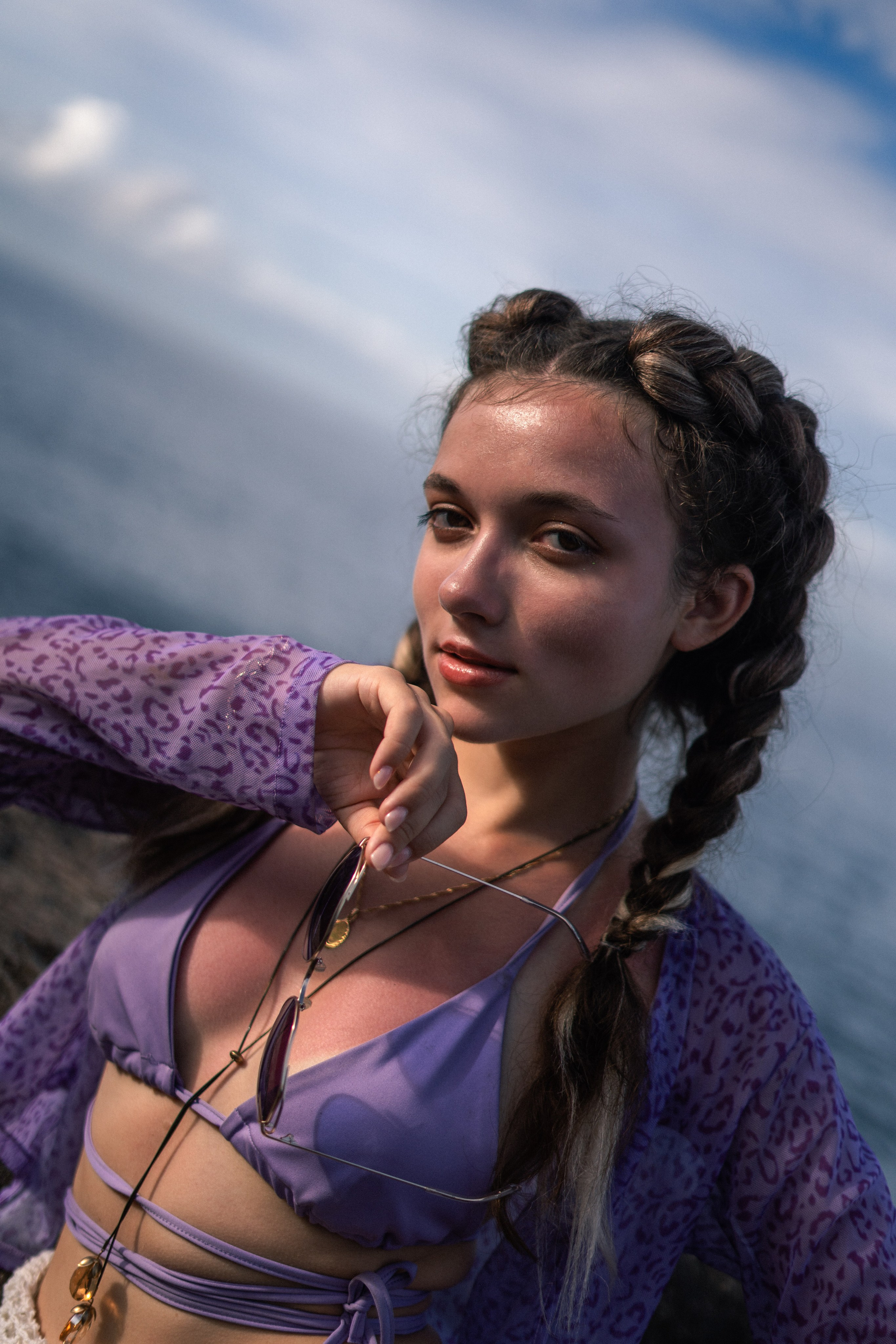 a girl in a purple swimsuit with rocks and the ocean in the background
