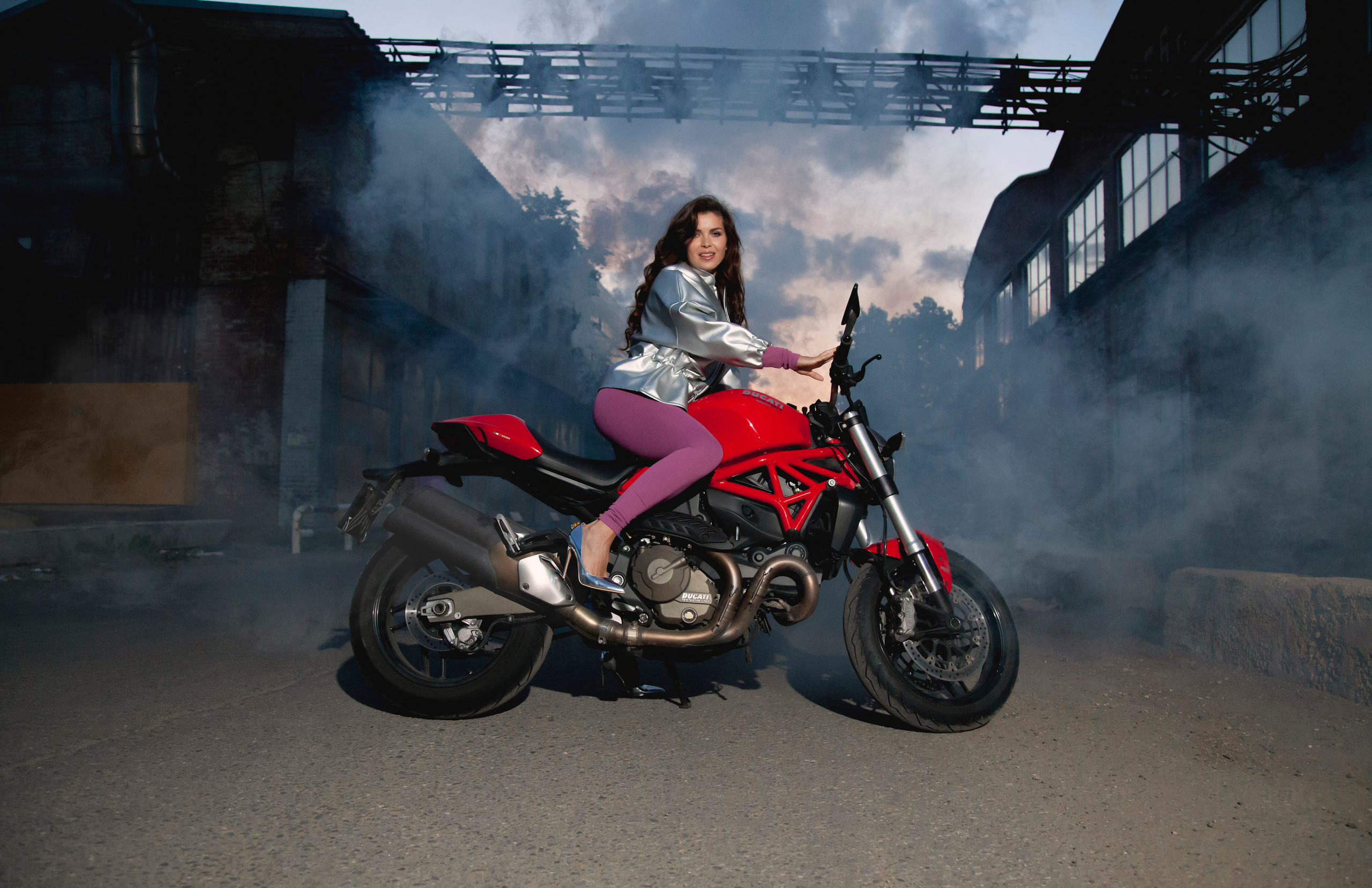 Девушка в кадре газует на своём красной мотоцикле.