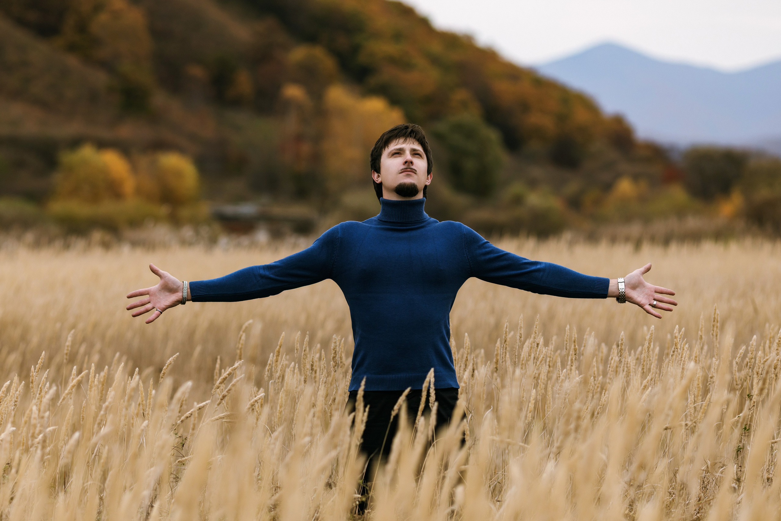 Выездная осенняя мужская фотосессия в стиле Павла Дурова на природе на фоне пожелтевшего поля и сопок с золотистыми деревьями. Автор снимка - портретный фотограф в Находке Олег Мороз