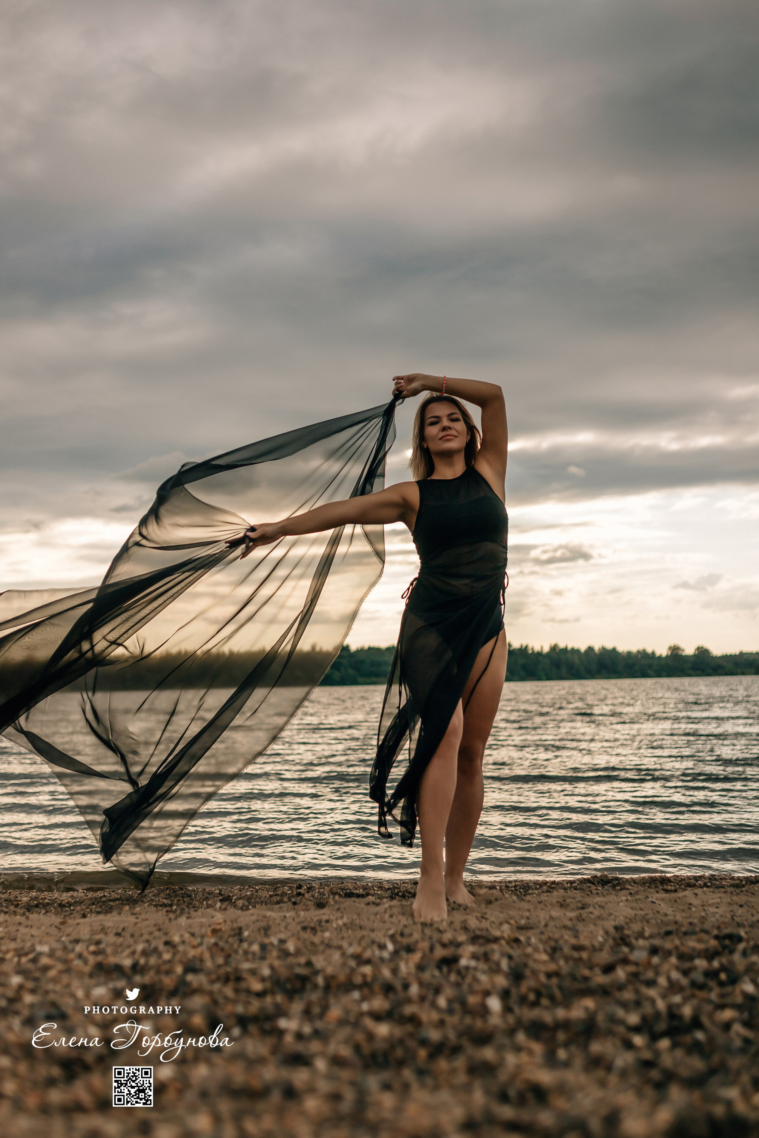 Фотосессия с черной тканью. Легкая черная вуаль летит на вертру. Фотосессия у реки черная серия с тканью. Девушка укуталась в черную ткань. Прогулка по набережной. Песок, речка, модель в черном. Качели над водой, Закат. Девушка лежит на песке. В зеленых деревьях