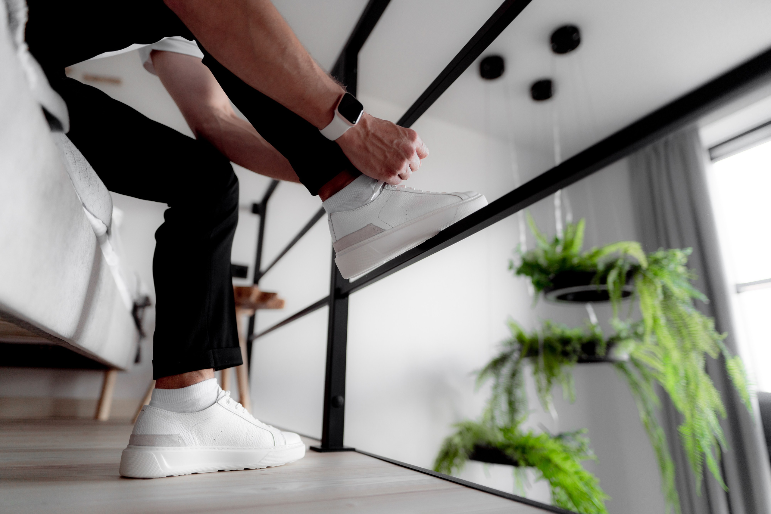 Жених завязывает белые кроссовки на сборах в квартире