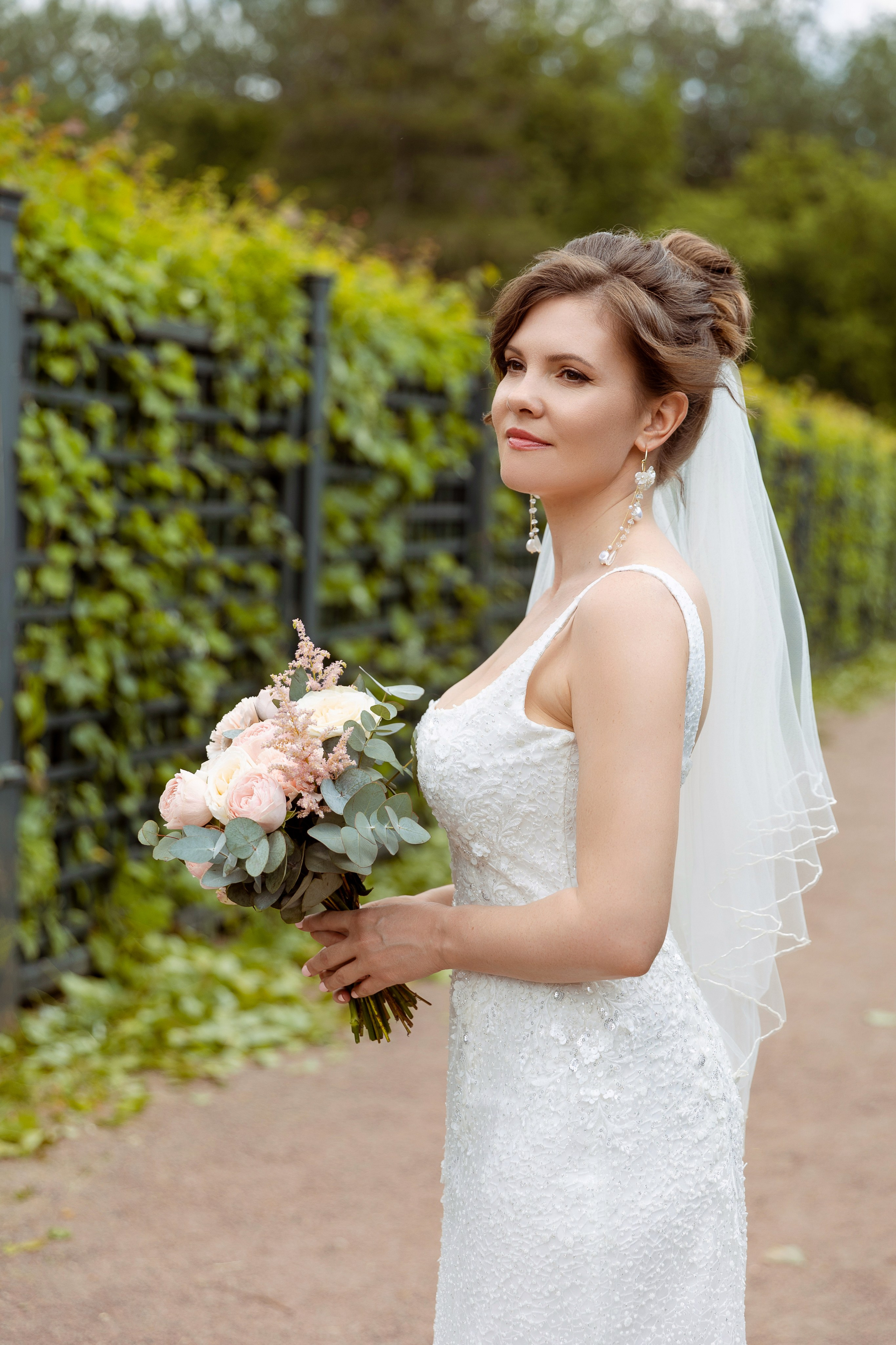 Невеста держит в руках букет цветов и романтично смотрит