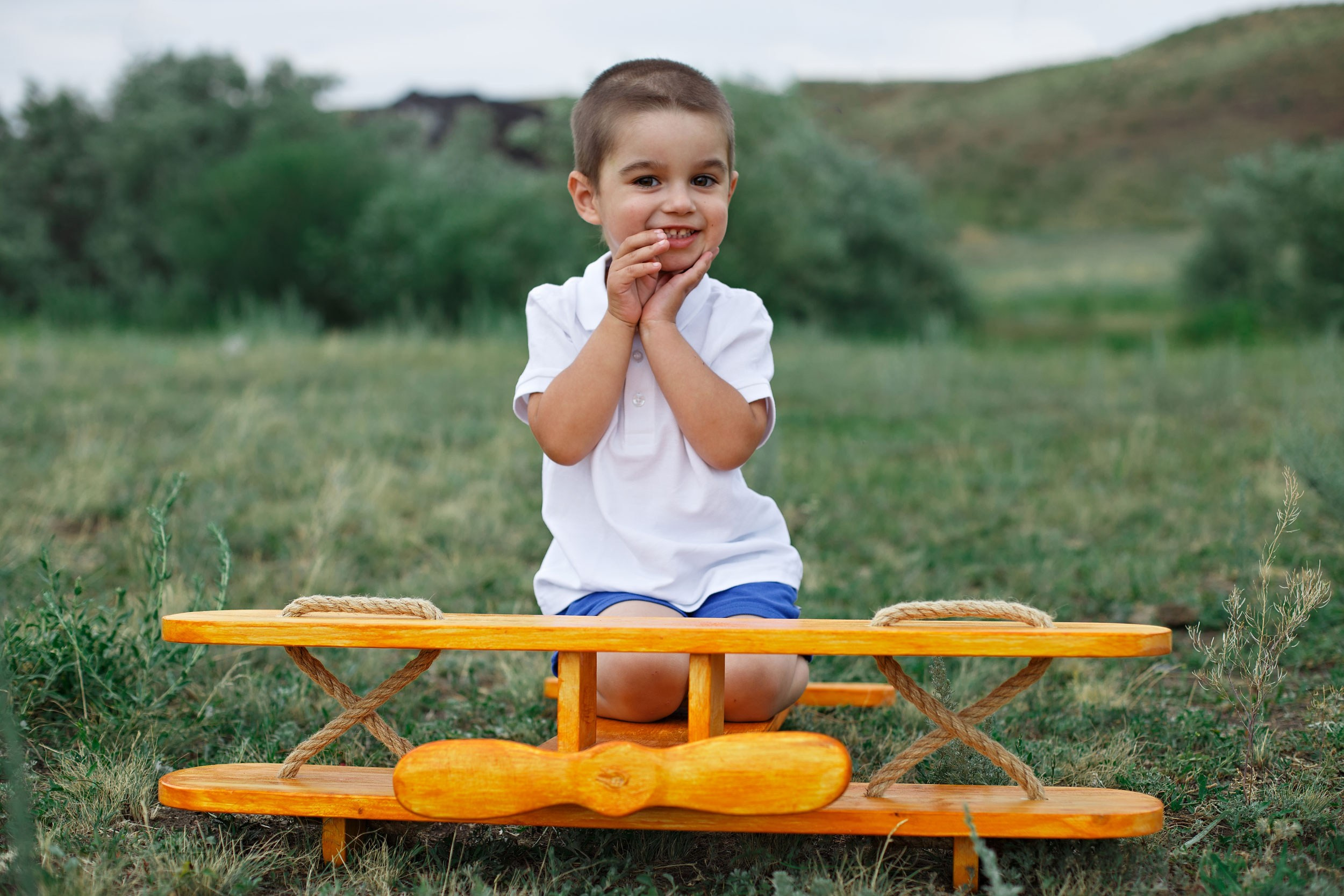 Счастливый ребенок  играет в поле с самолетом