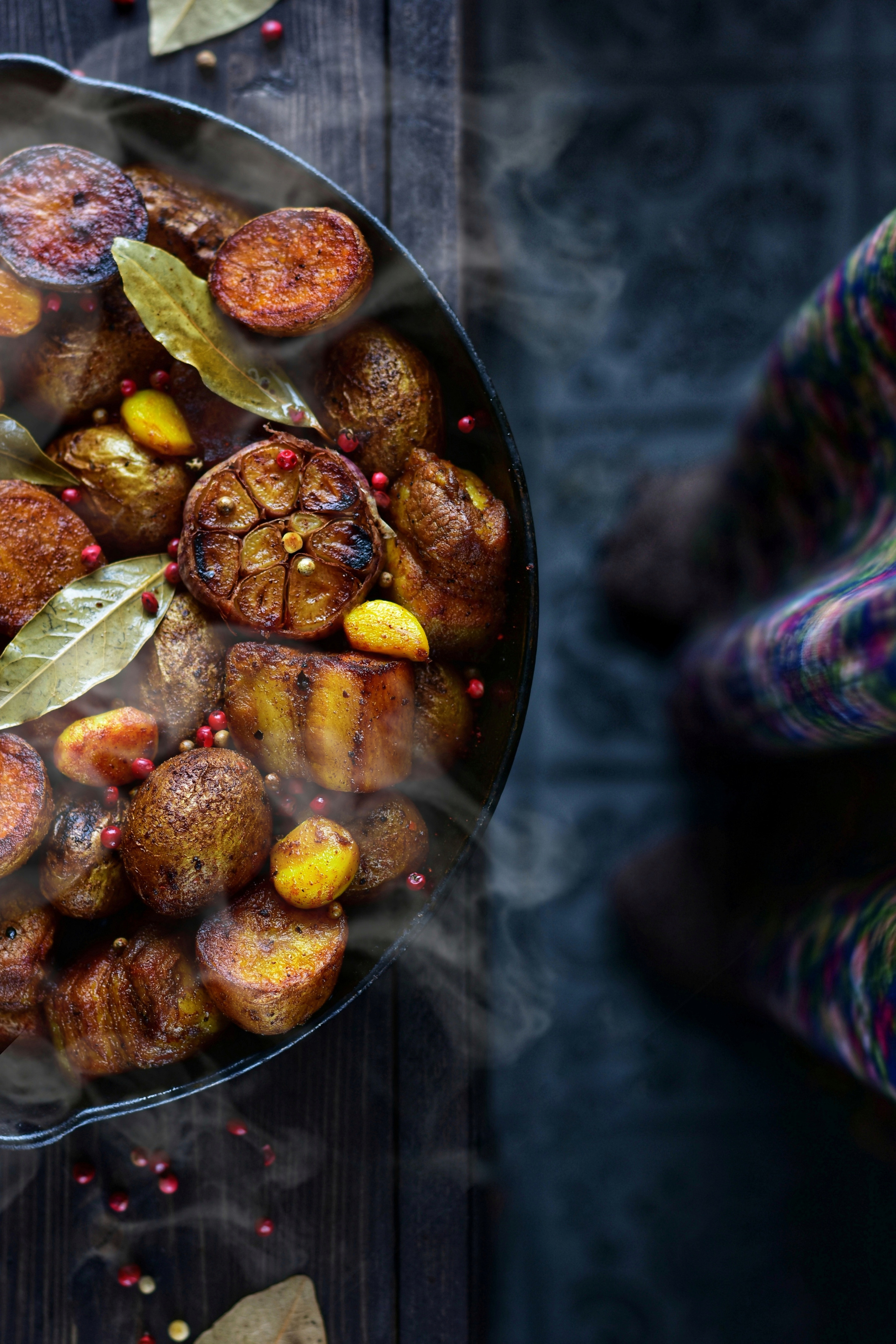 котелок, наполненный жареным картофелем, стоит на деревянном столе.