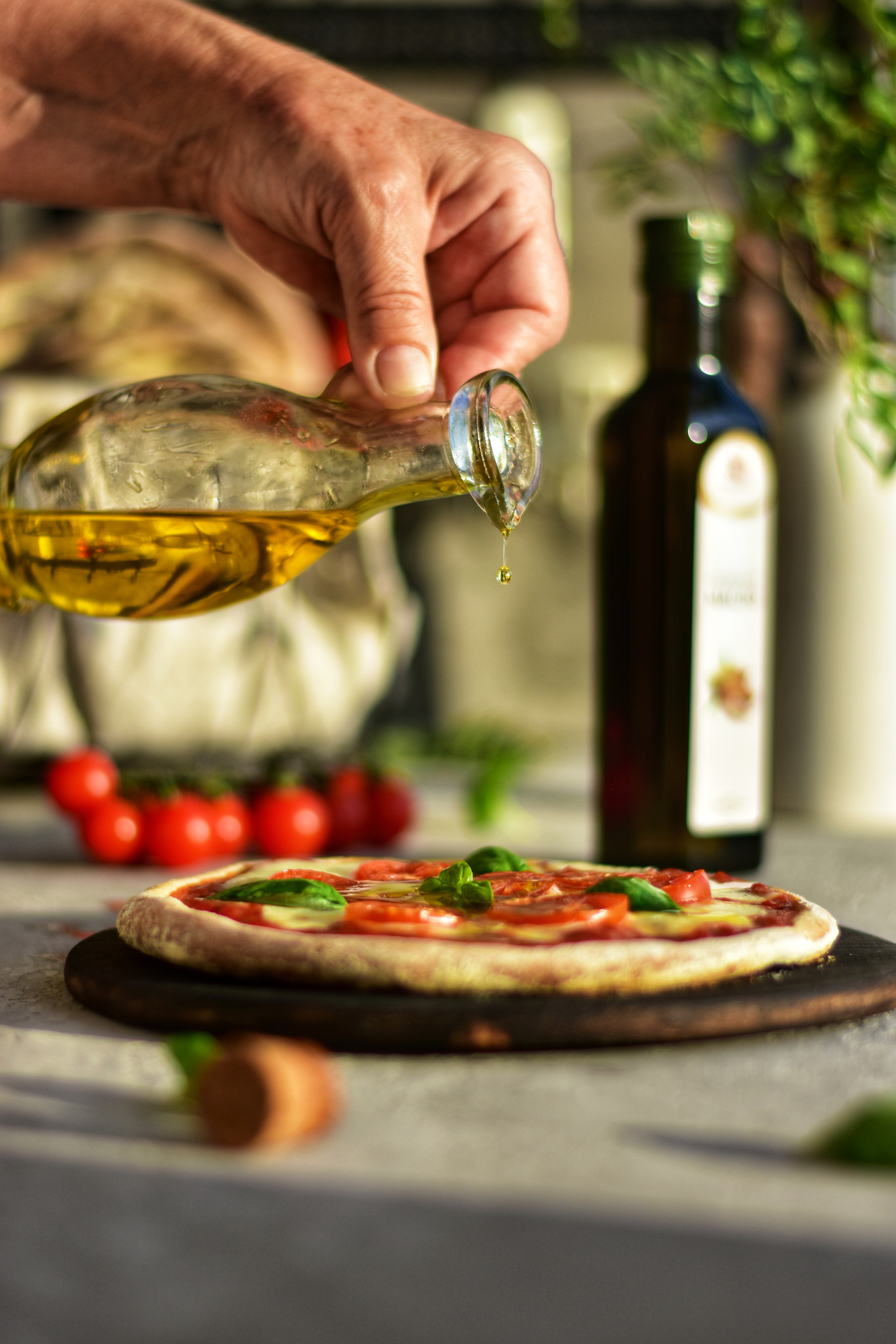 женская рука льет оливковое масло на пиццу