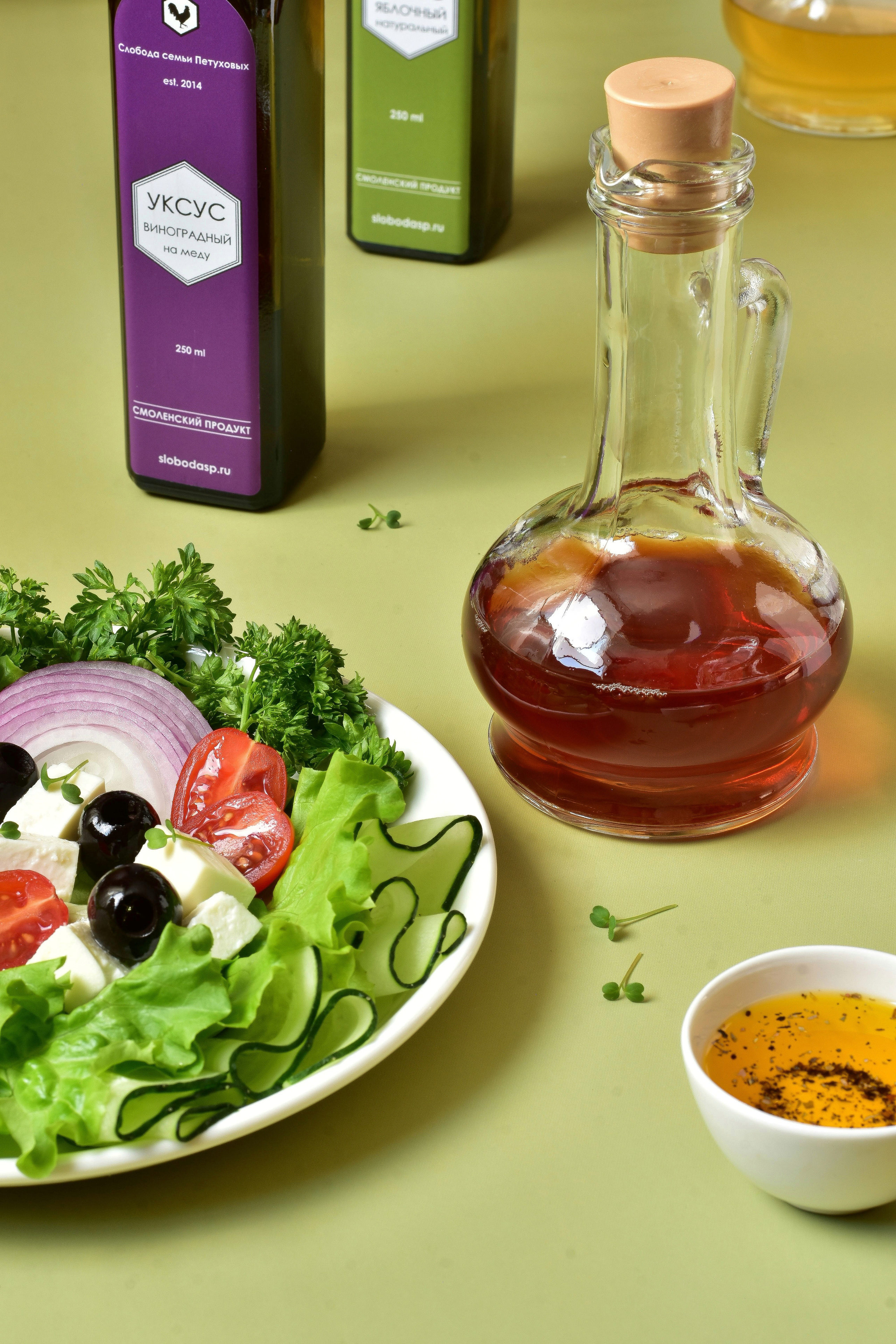Фото композиция яблочный и виноградный уксус и тарелка салата на столе
