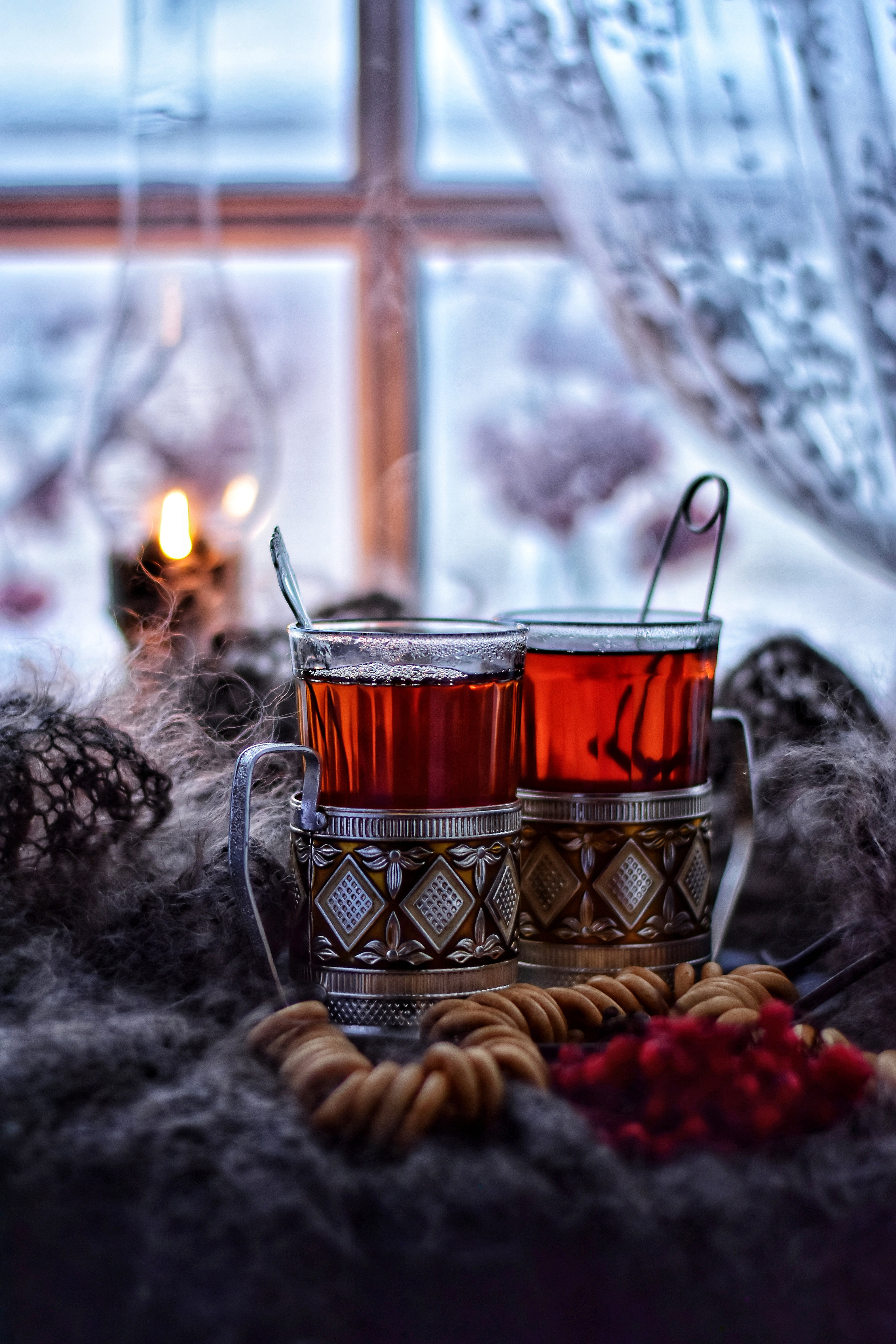 два стакана чая в подстаканниках с сушками на фоне зимнего окна