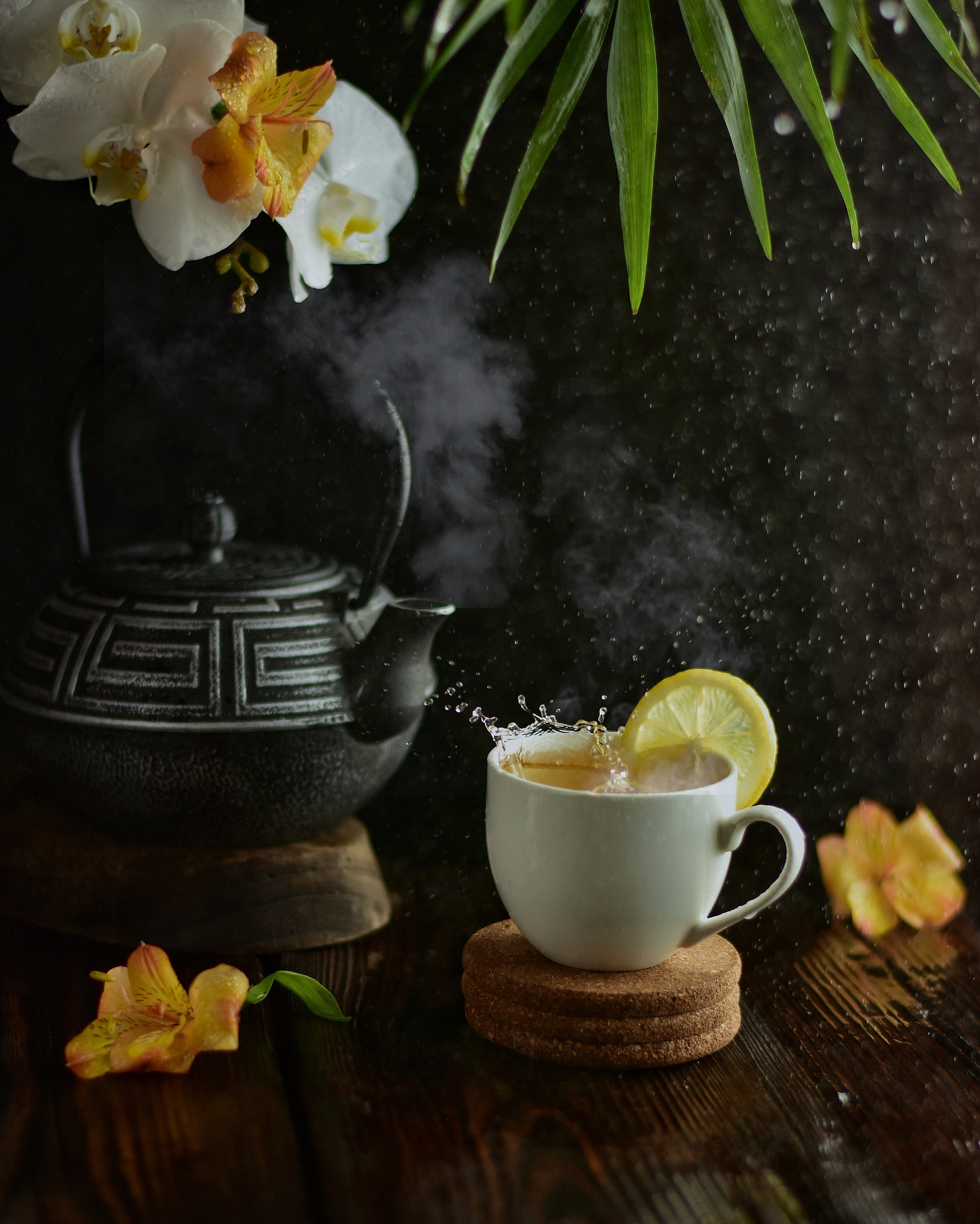 чугунный чайник и чашка чая с долькой лимона на подставке на деревянном столе