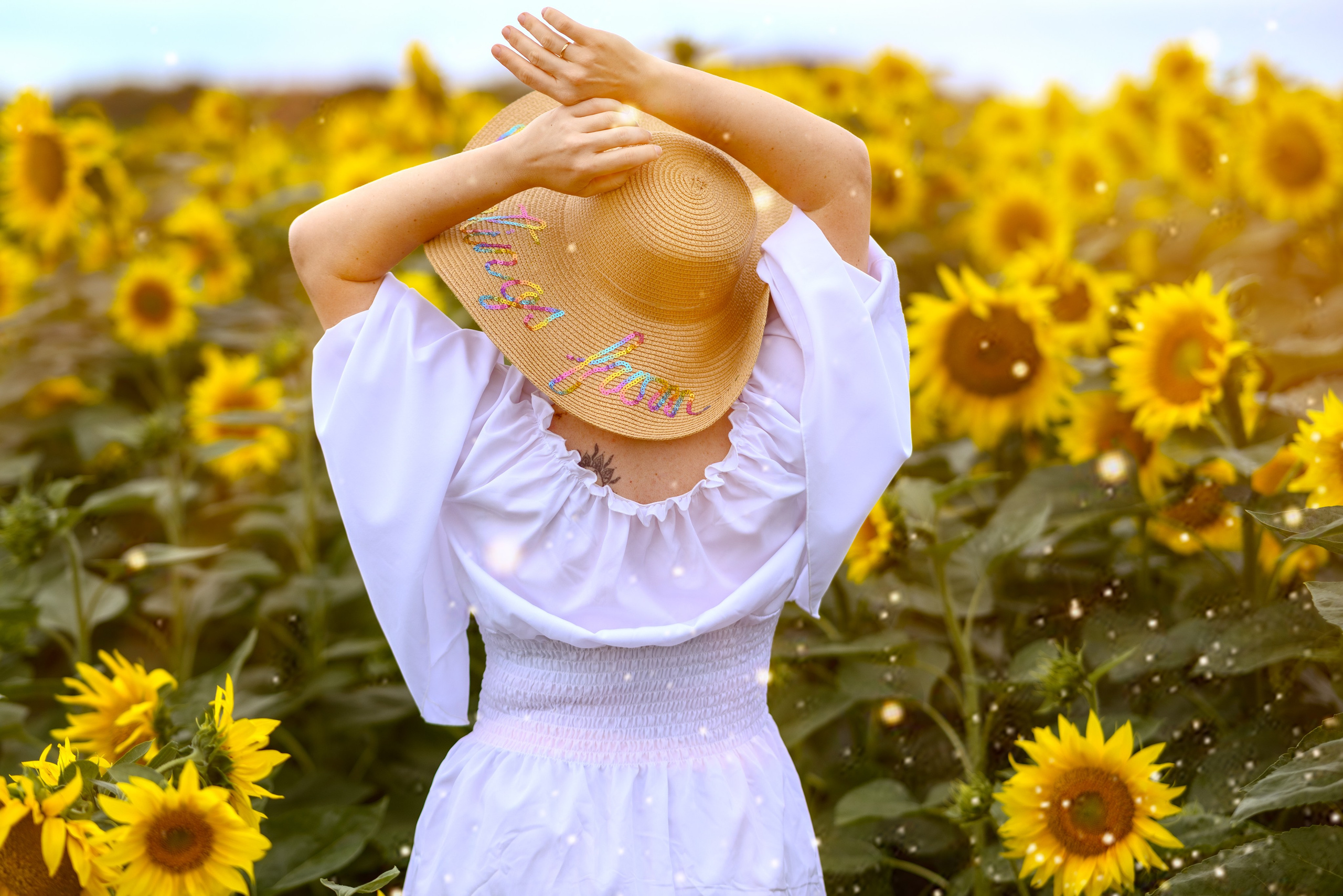 Фотосъемка на природе - девушка в шляпе спиной к зрителю среди поля подсолнухов