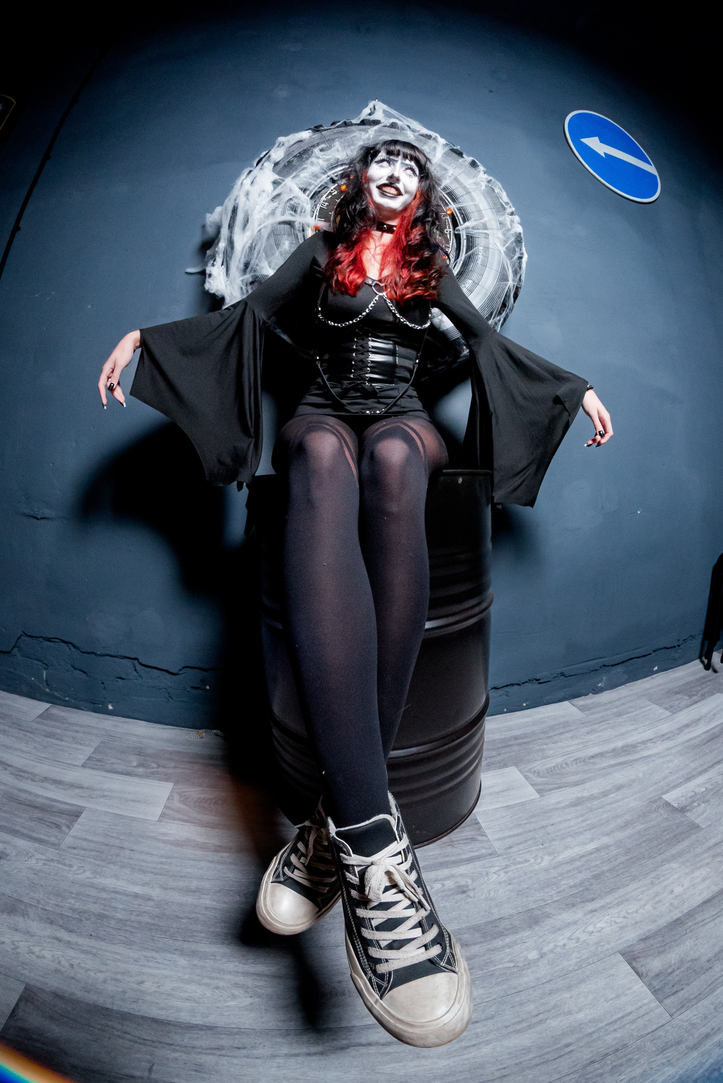 Фотосъемка с объективом «рыбий глаз» — девушка в черном платье сидит на огромной бочке.