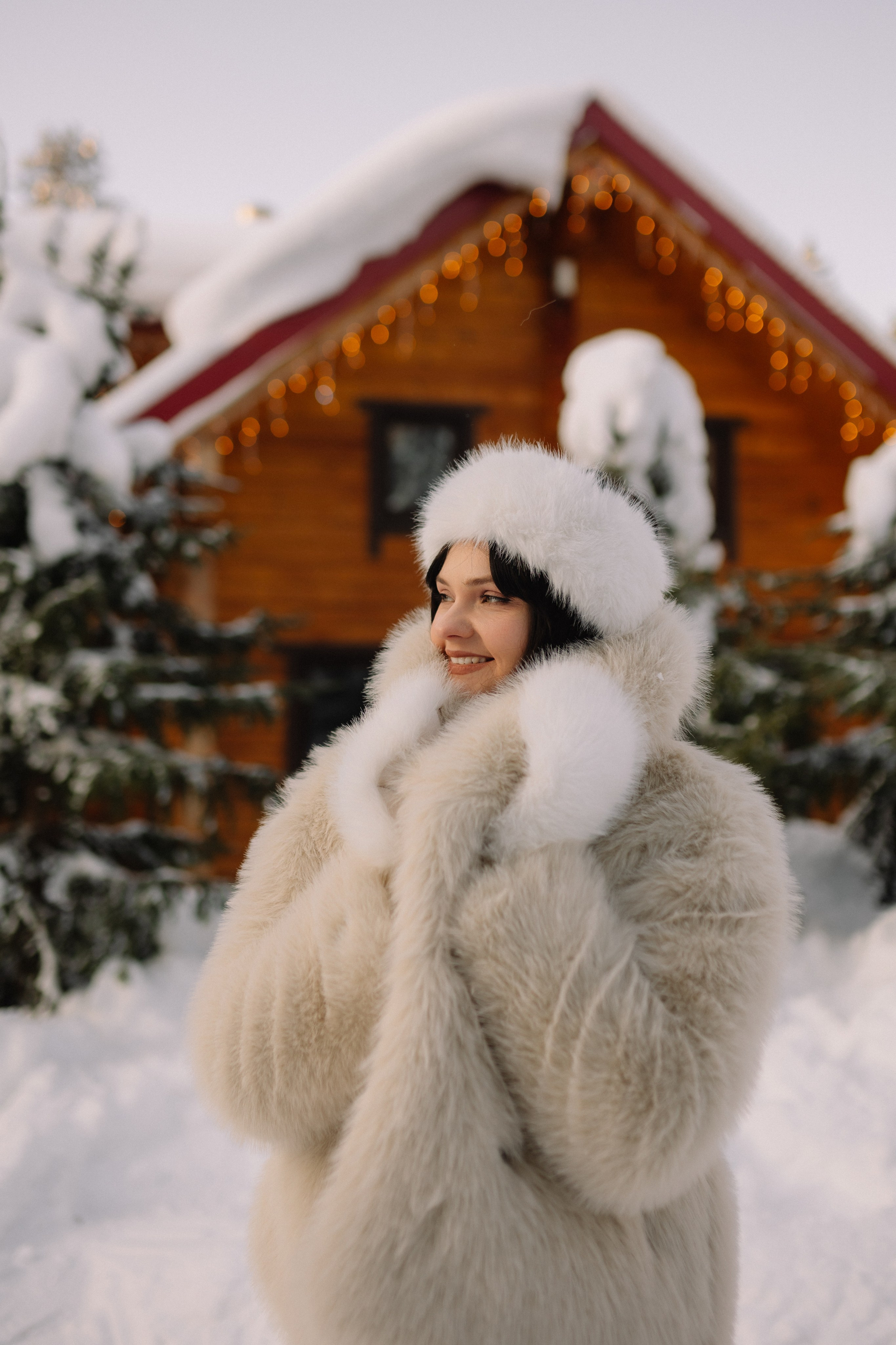 Девушка улыбается на фоне белоснежного леса турбазы в Мурманске.  