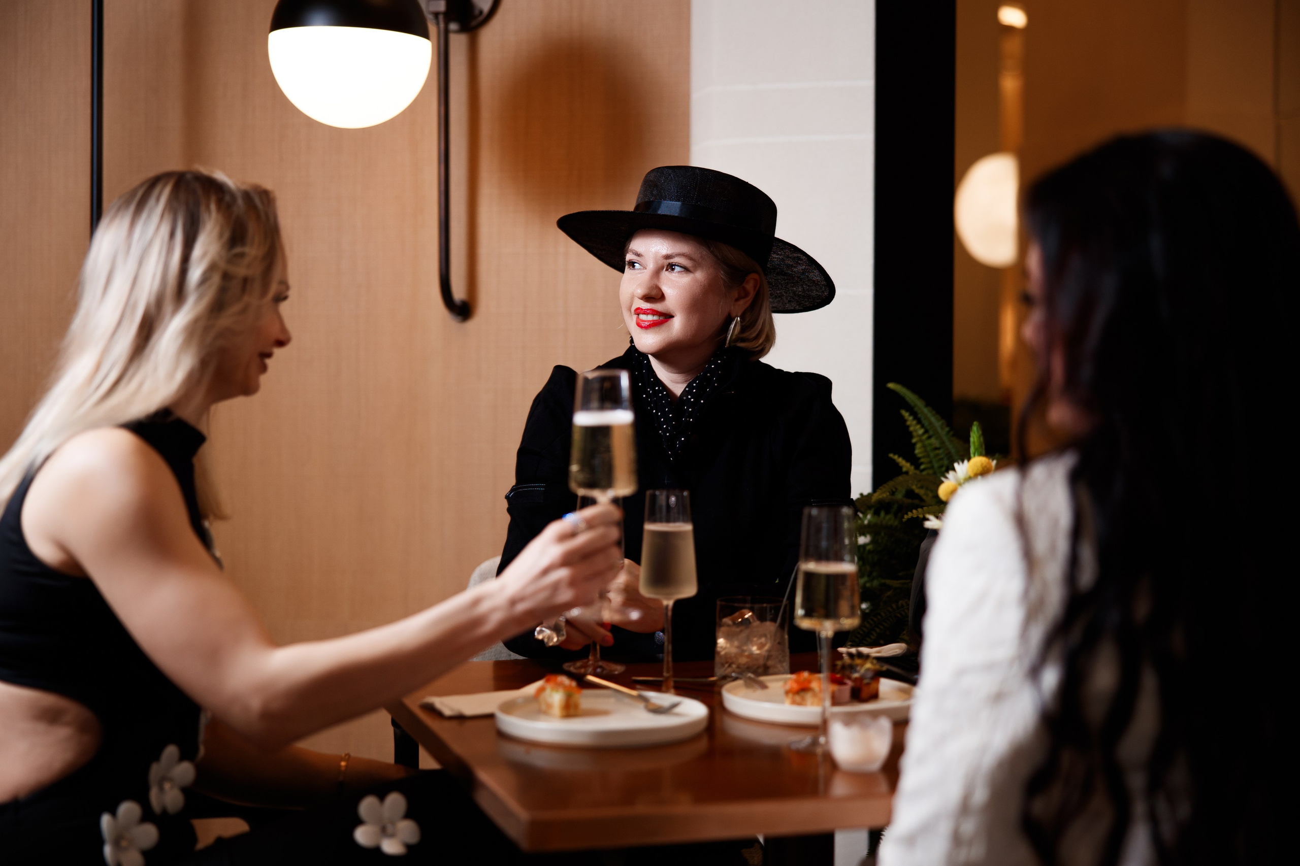 Ужин: Девушки в элегантных образах ведут беседу за бокалом вина в ресторане.