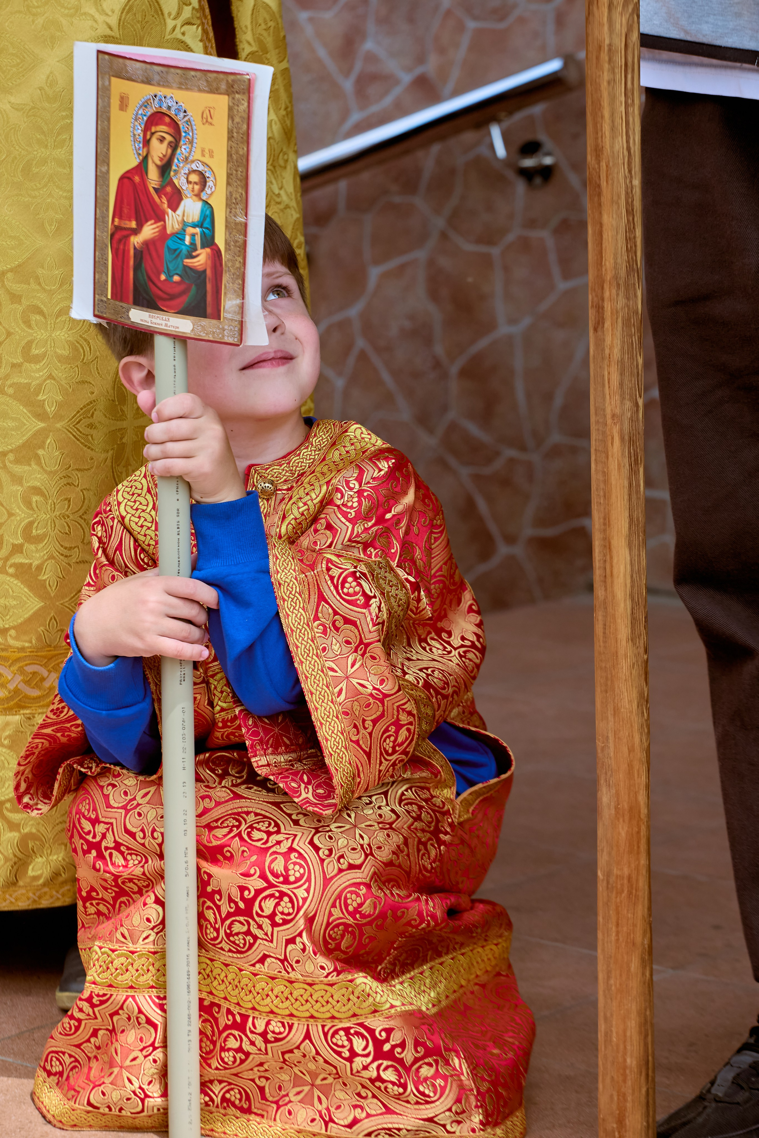 В кадре маленький алтарник в облачении с иконой Богородицы