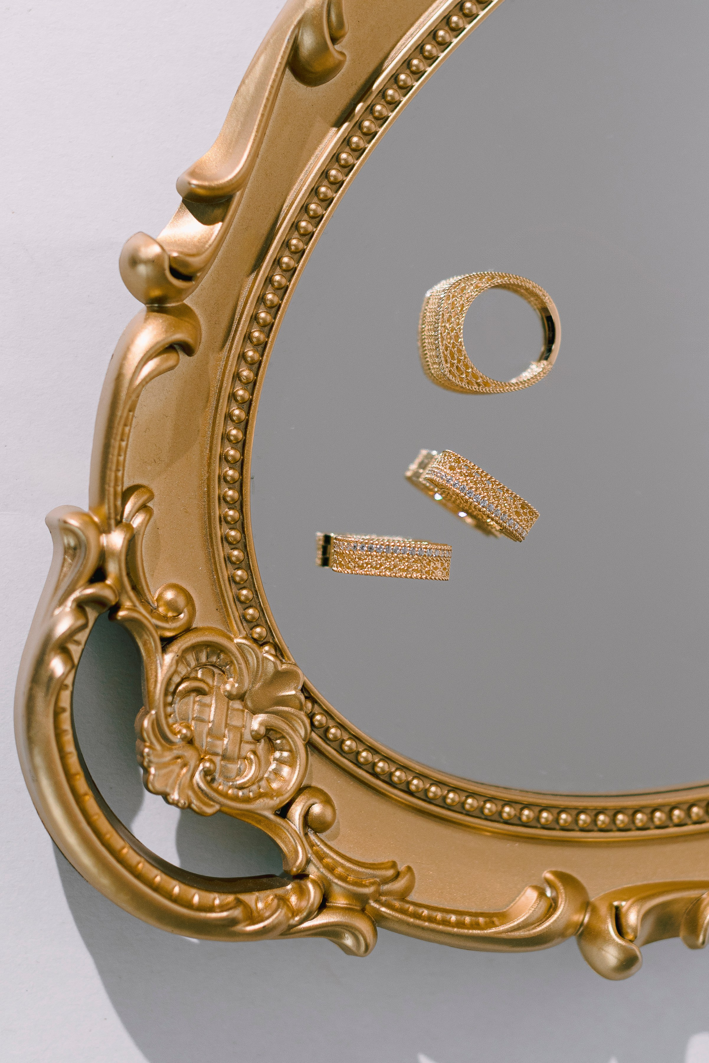 золотые серьги лежат на зеркальном подносе