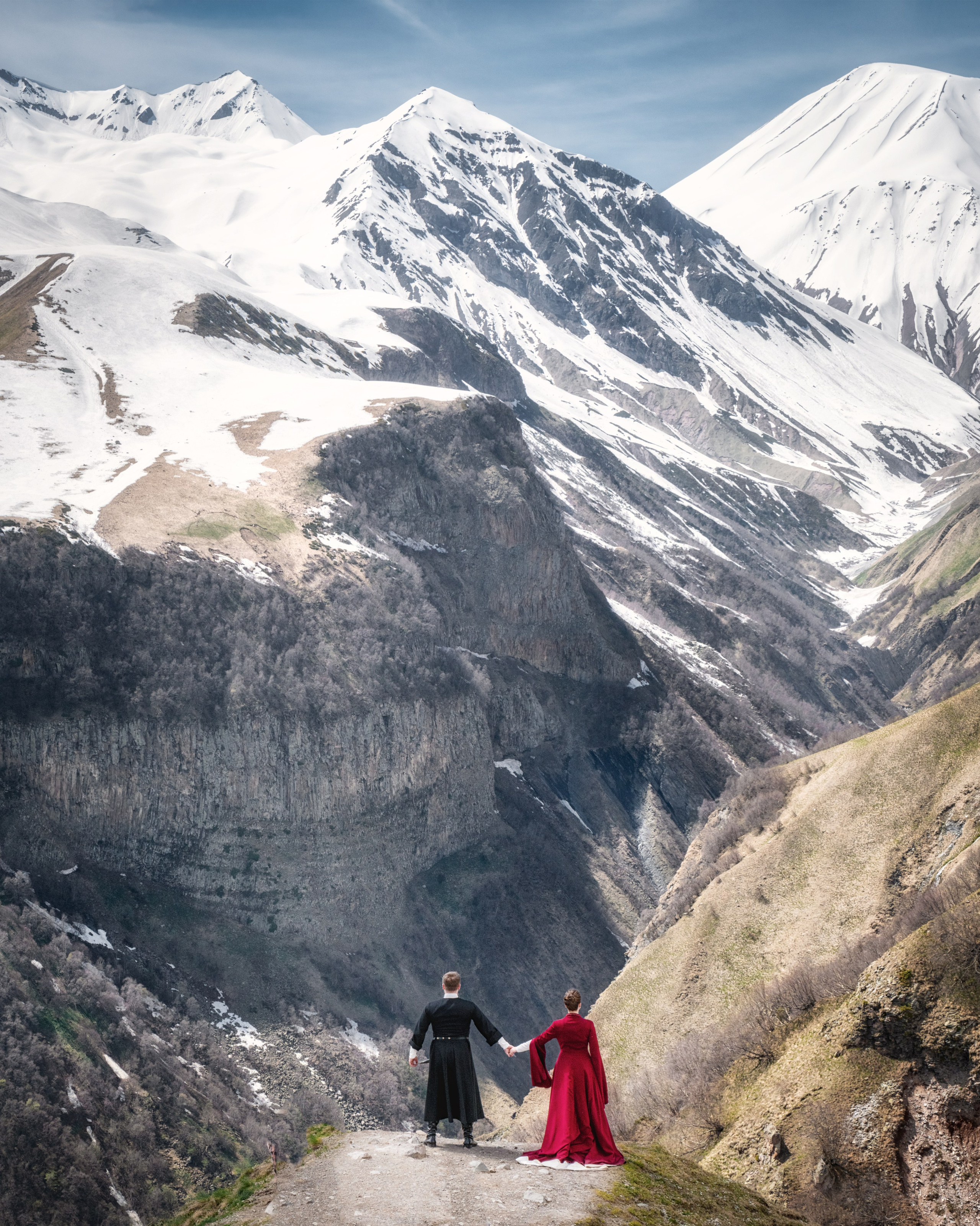 Мужчина и женщина в национальных грузинских свадебных костюмах смотрят на горы