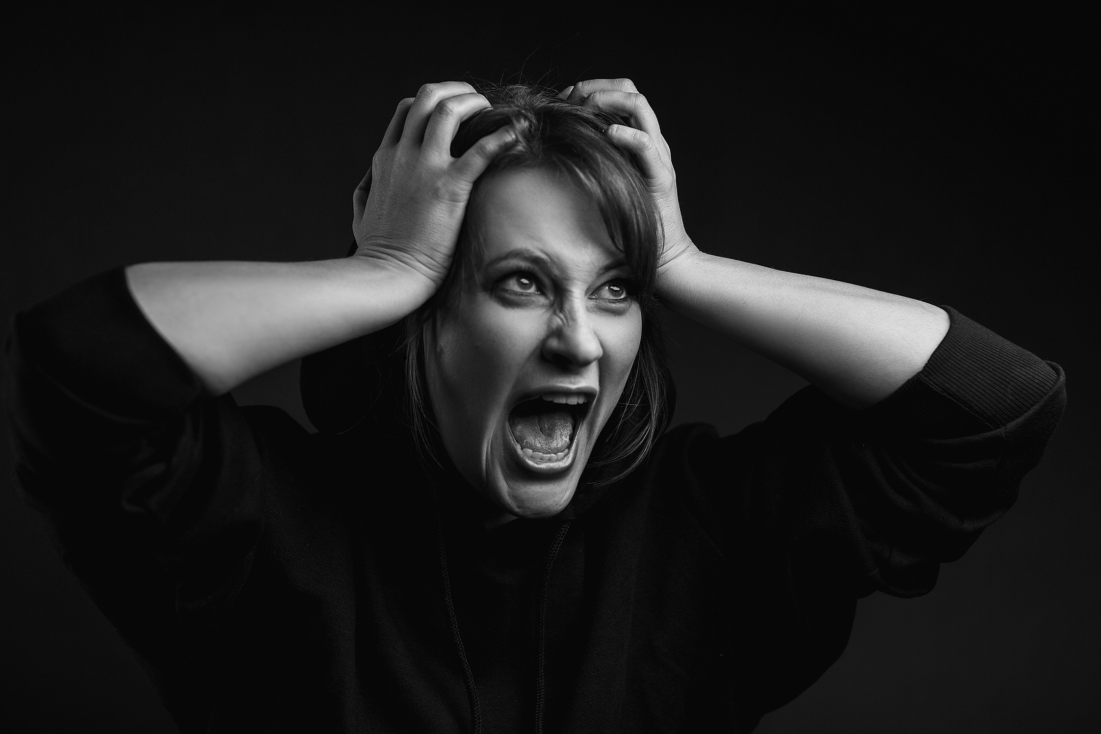 черно-белый портрет девушки в темной студии которая кричит