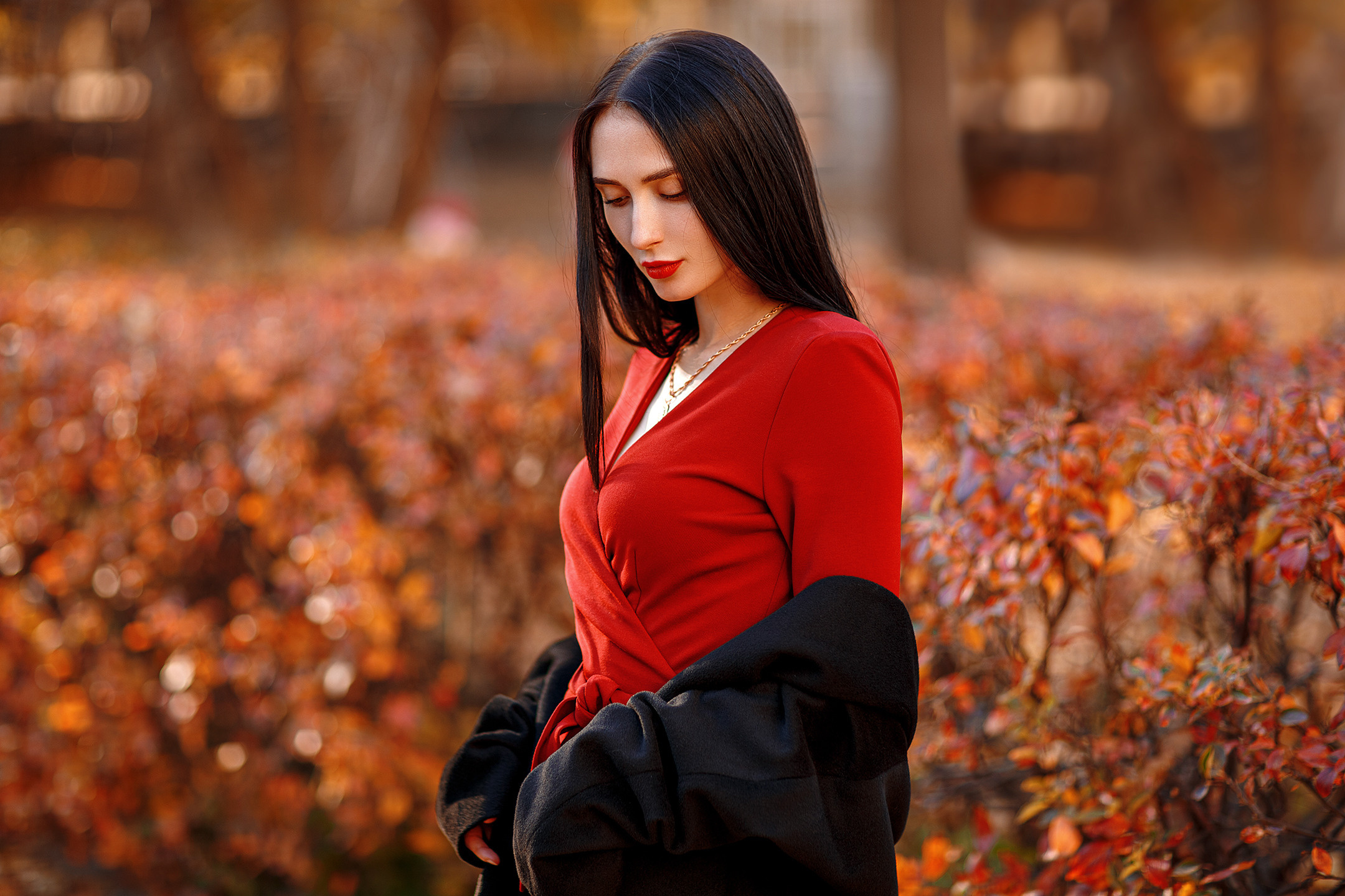 брюнетка в ярком красном платье в осенней листве