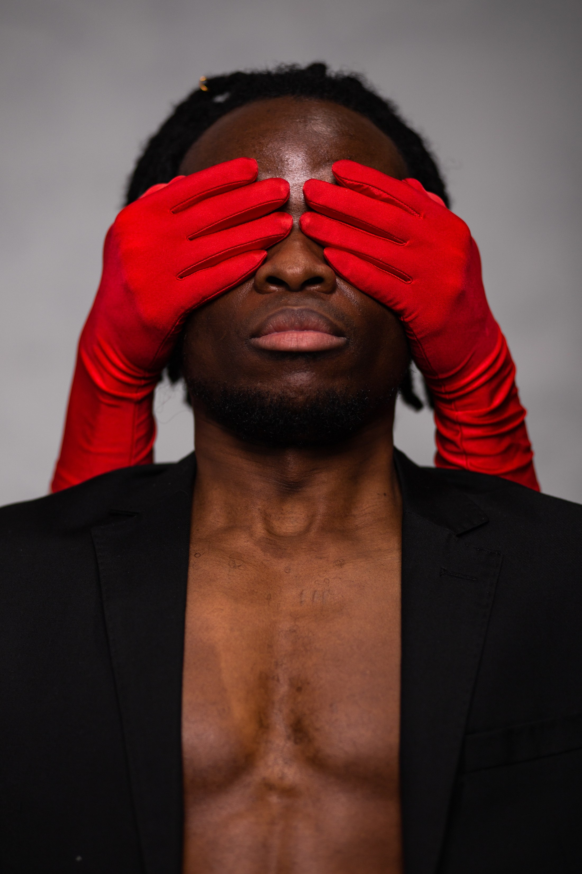 Красные руки закрывают глаза черному парню