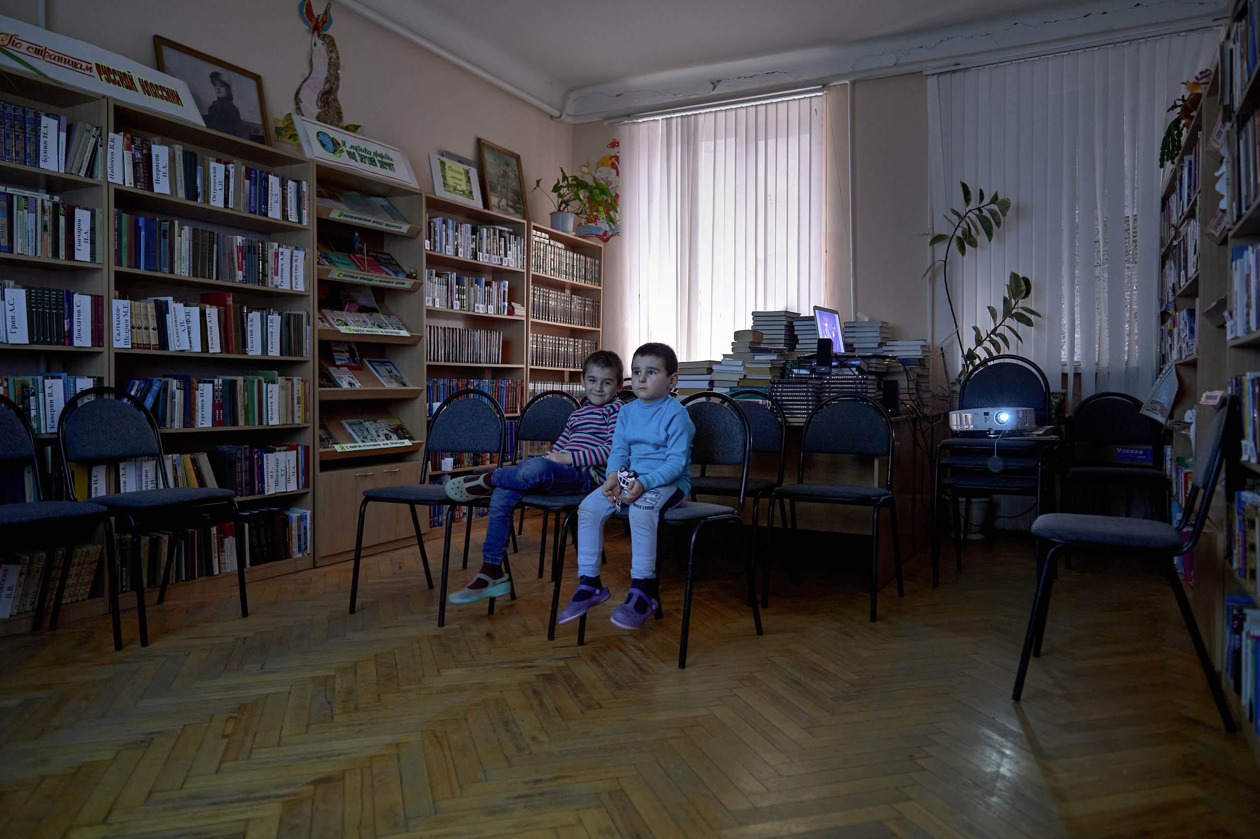 Children watch cartoons in the library hall of the cultural center, which houses a temporary refugee accommodation center in the village of Krasnogornyatsky, February 26, 2022.