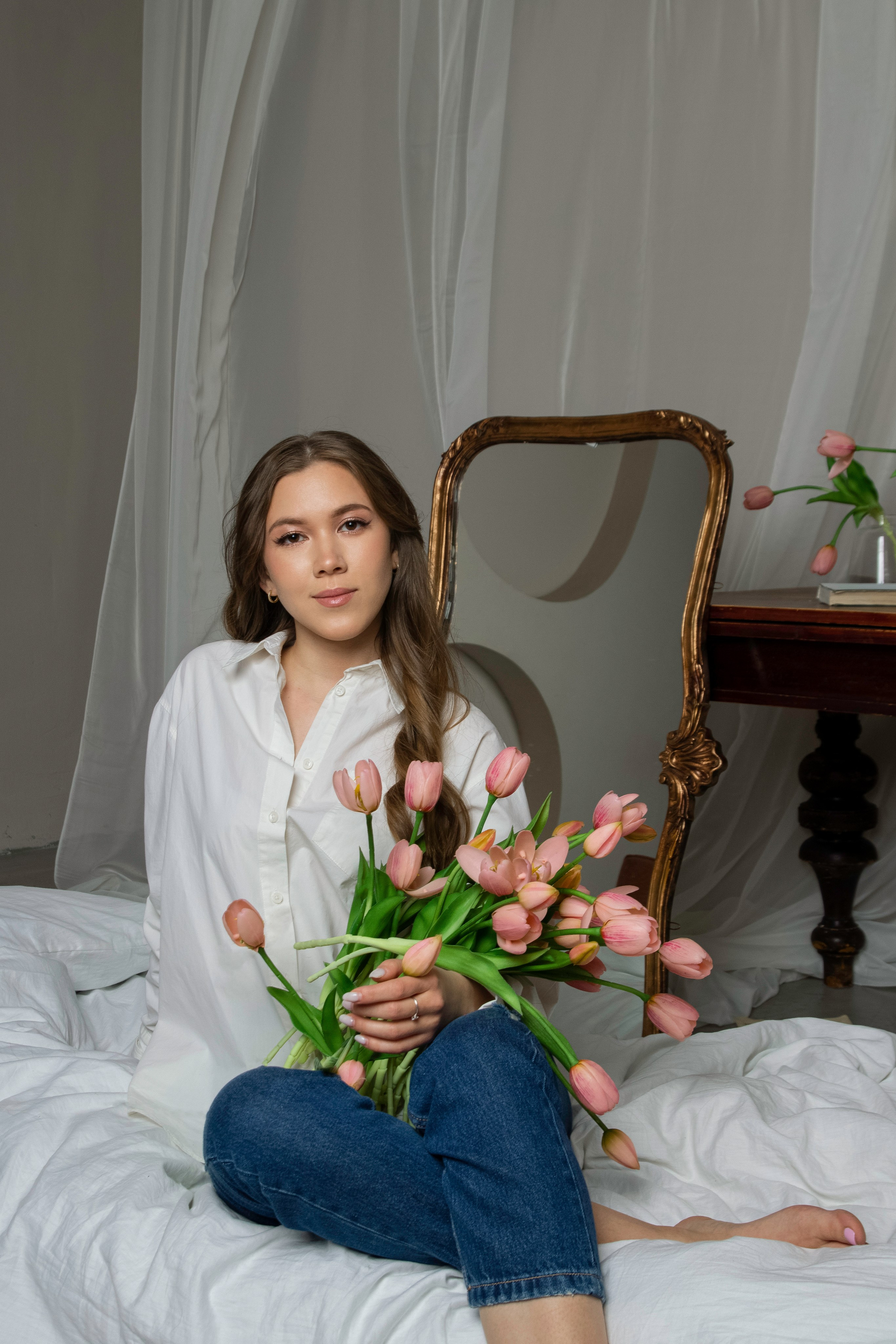 девушка фотографируется на кровати с цветами