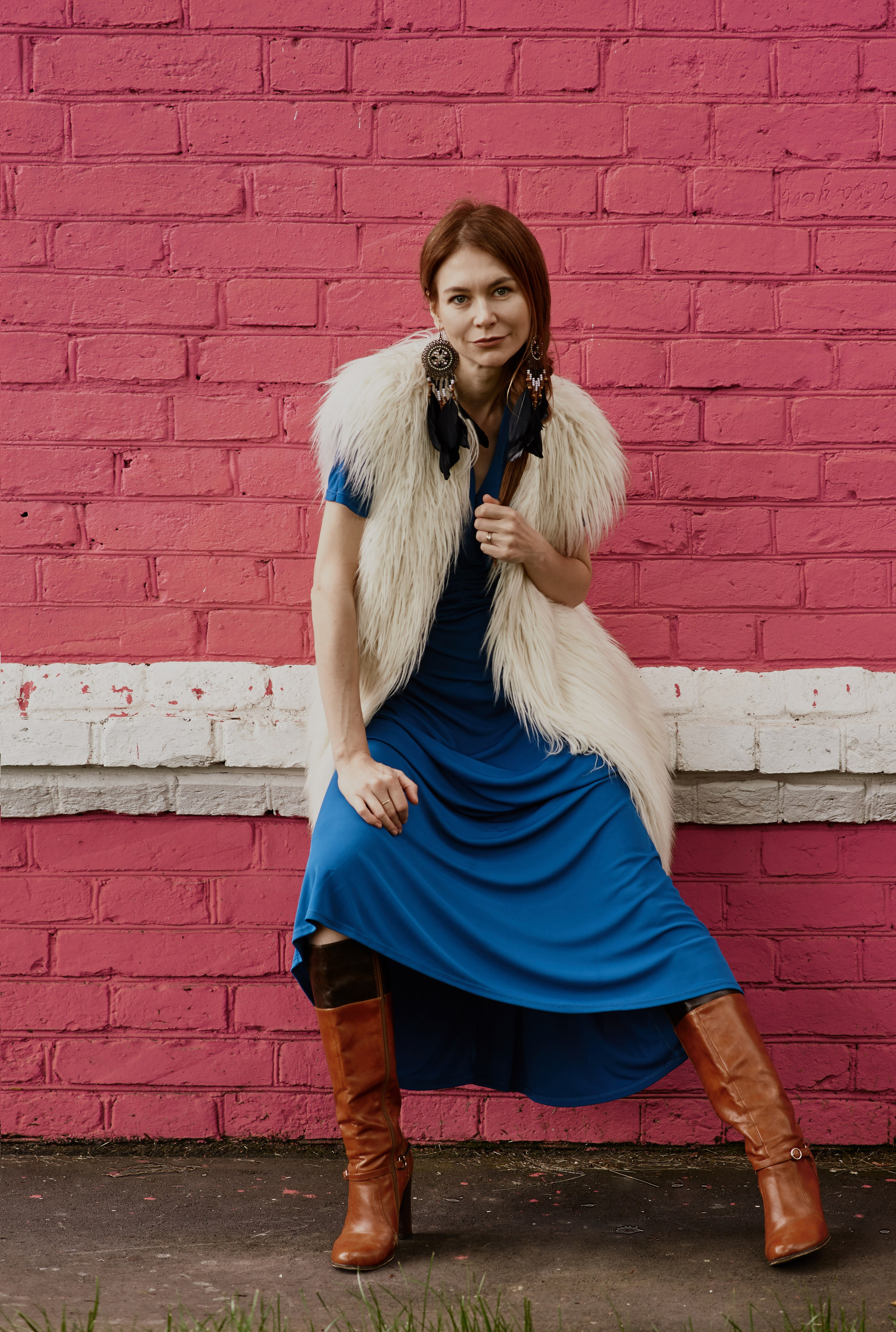 Фотосессия девушки на фоне кирпичной стены в жилете из искусственного белого меха