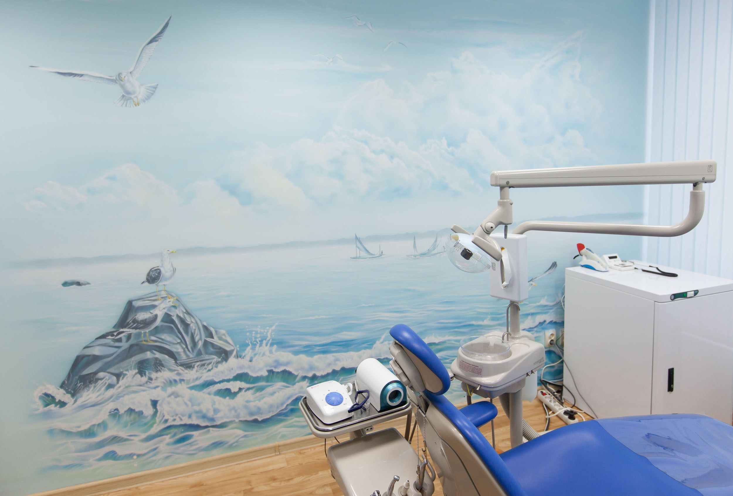 Стоматологический кабинет в голубых тонах с рисунком на стене.