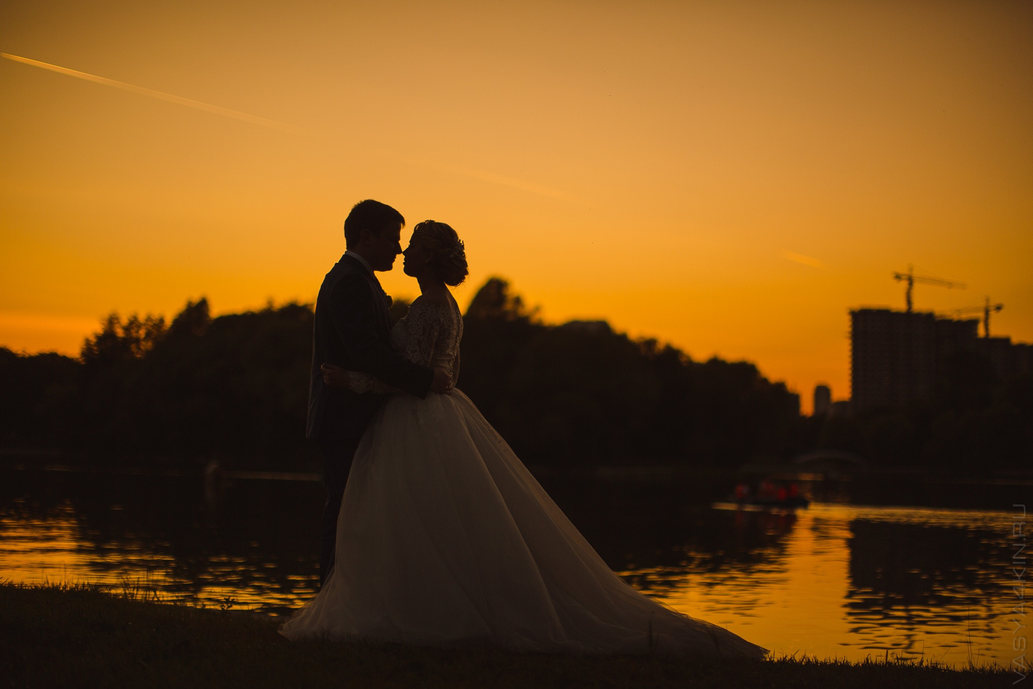 Пара стоит на фоне заходящего солнца, объятиями раскрывая свою нежность и силу любви