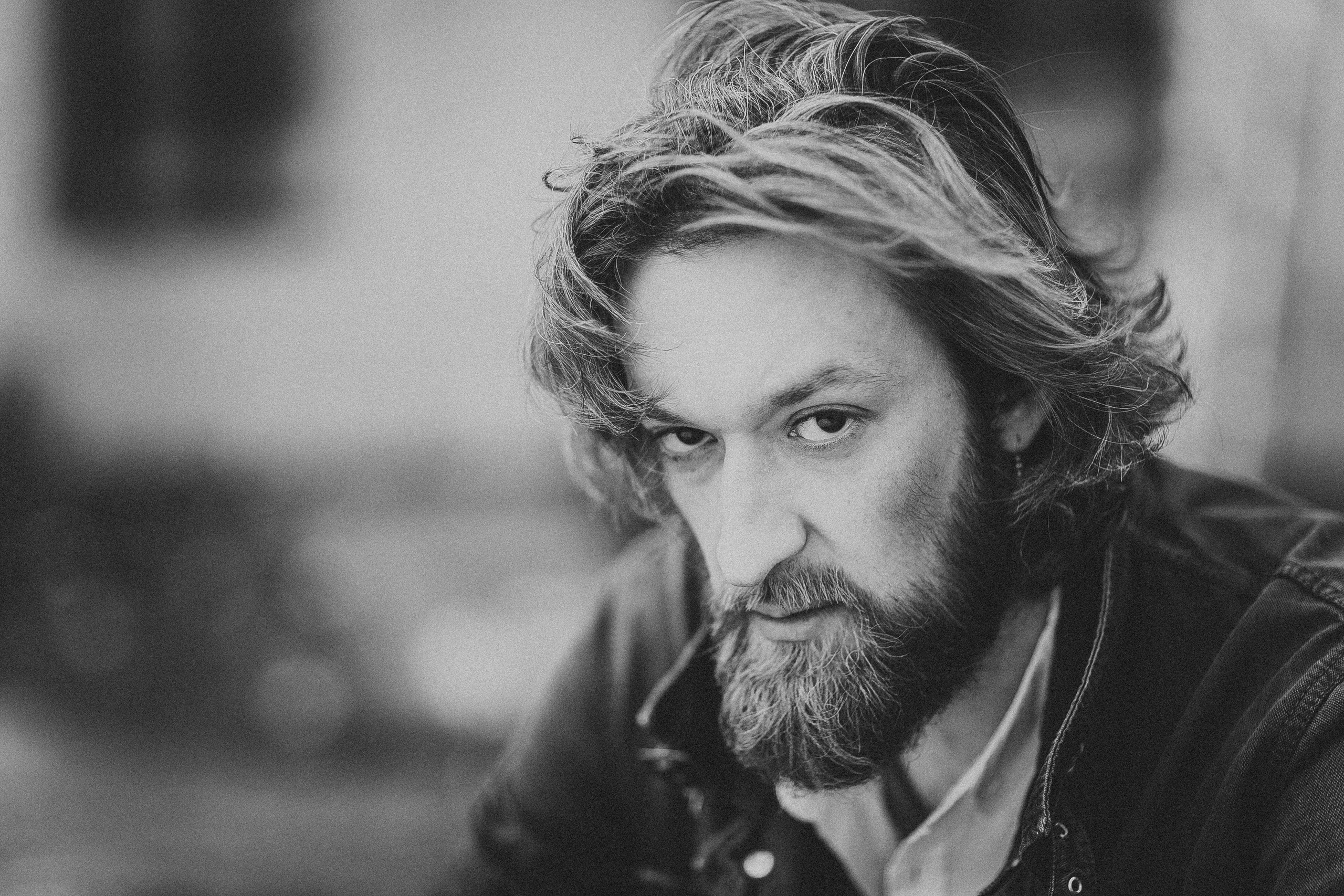 брутальный длинноволосый мужчина с бородой и суровым взглядом