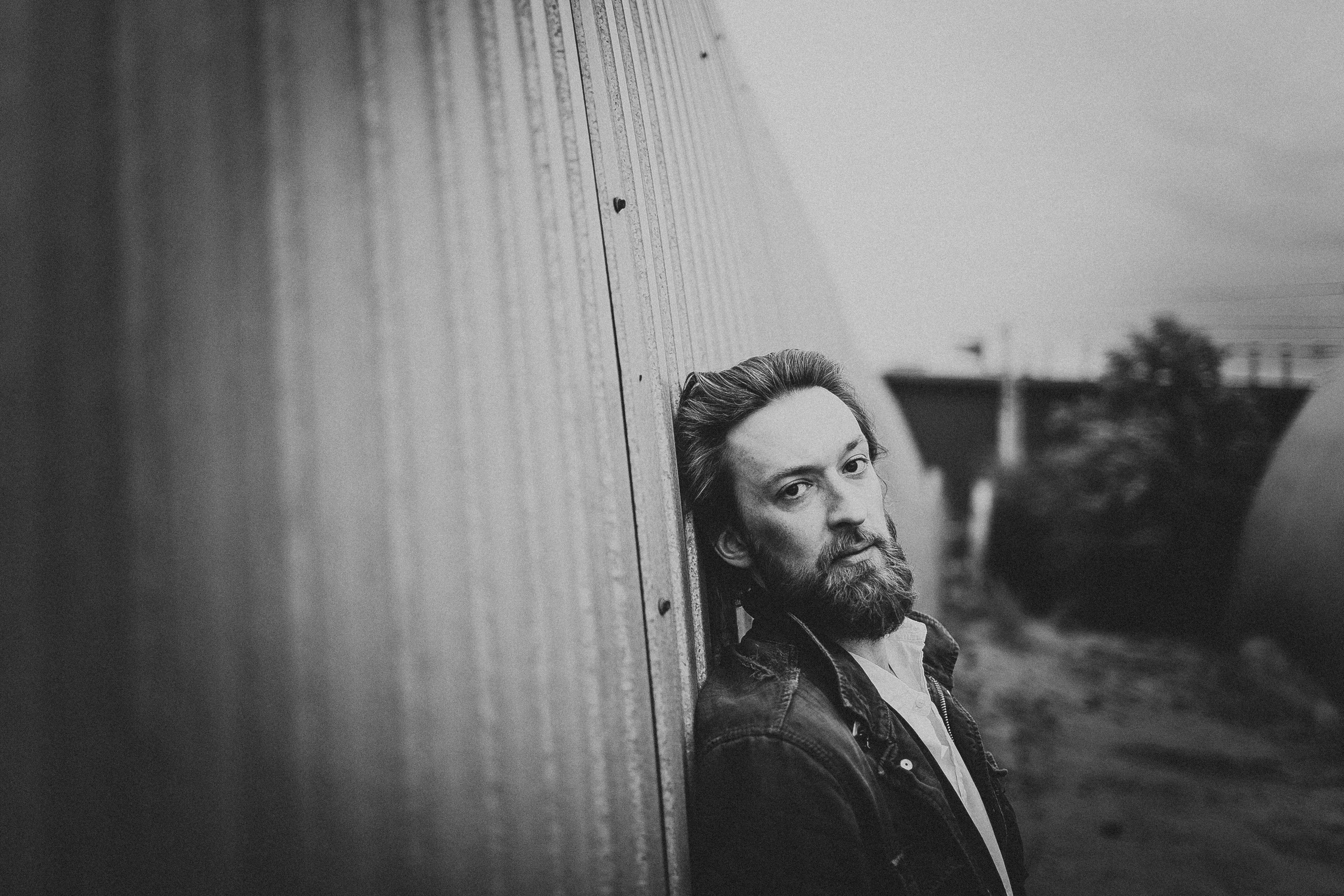 портрет брутального мужчины прислонившегося к забору