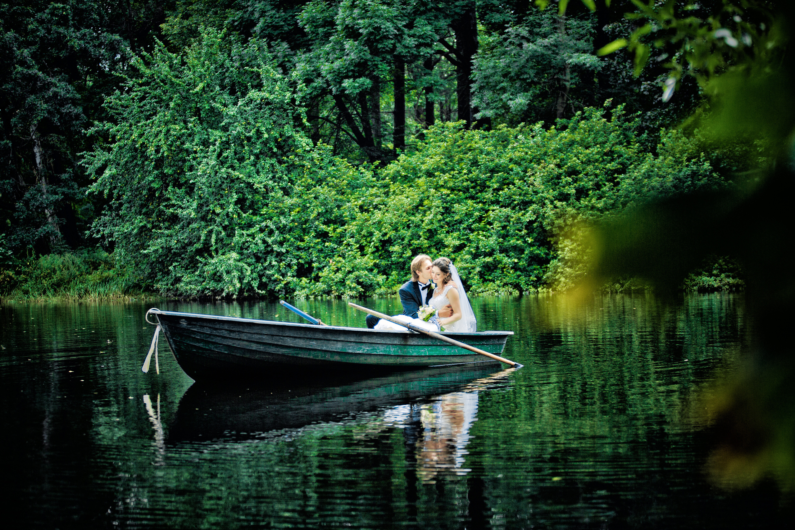жених и невеста плывут на лодке по пруду в буйстве зелени