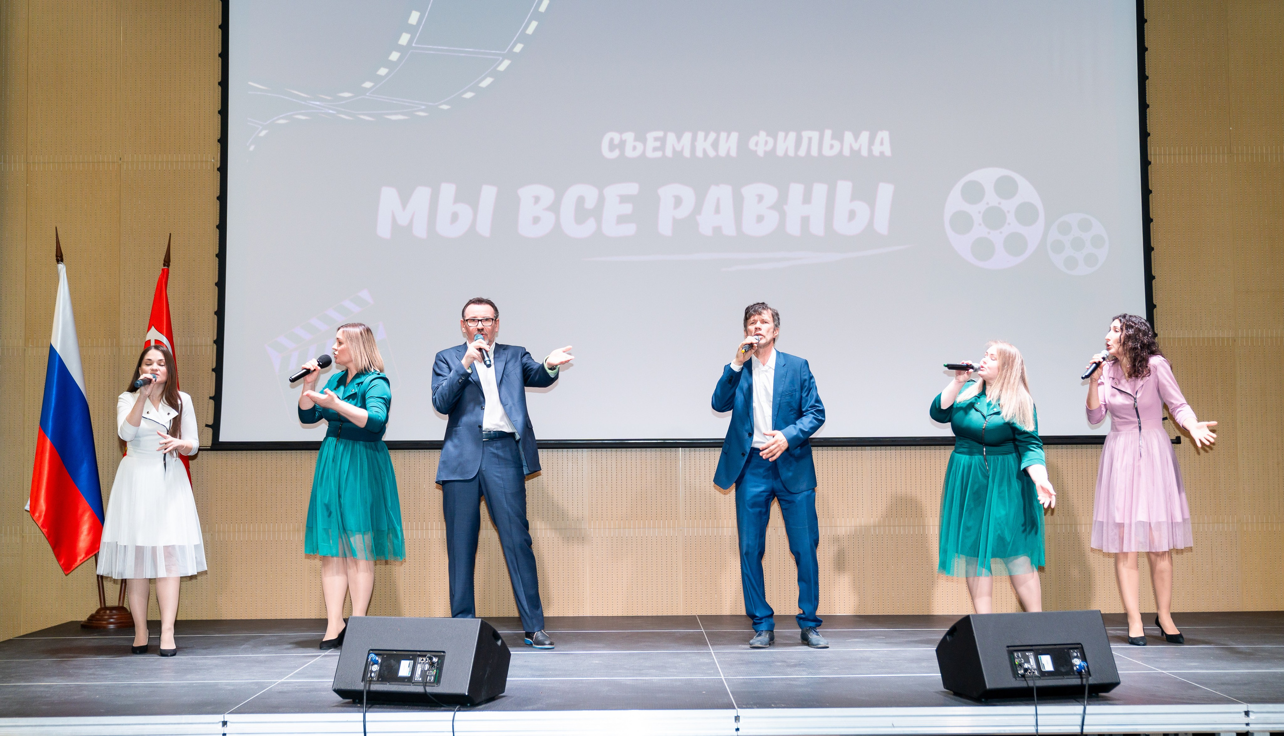 Ведущий в зелёном пиджаке и красном галстуке эмоционально выступает на сцене инклюзивного бала «Мы все равны». Фото Евгения Мальцева