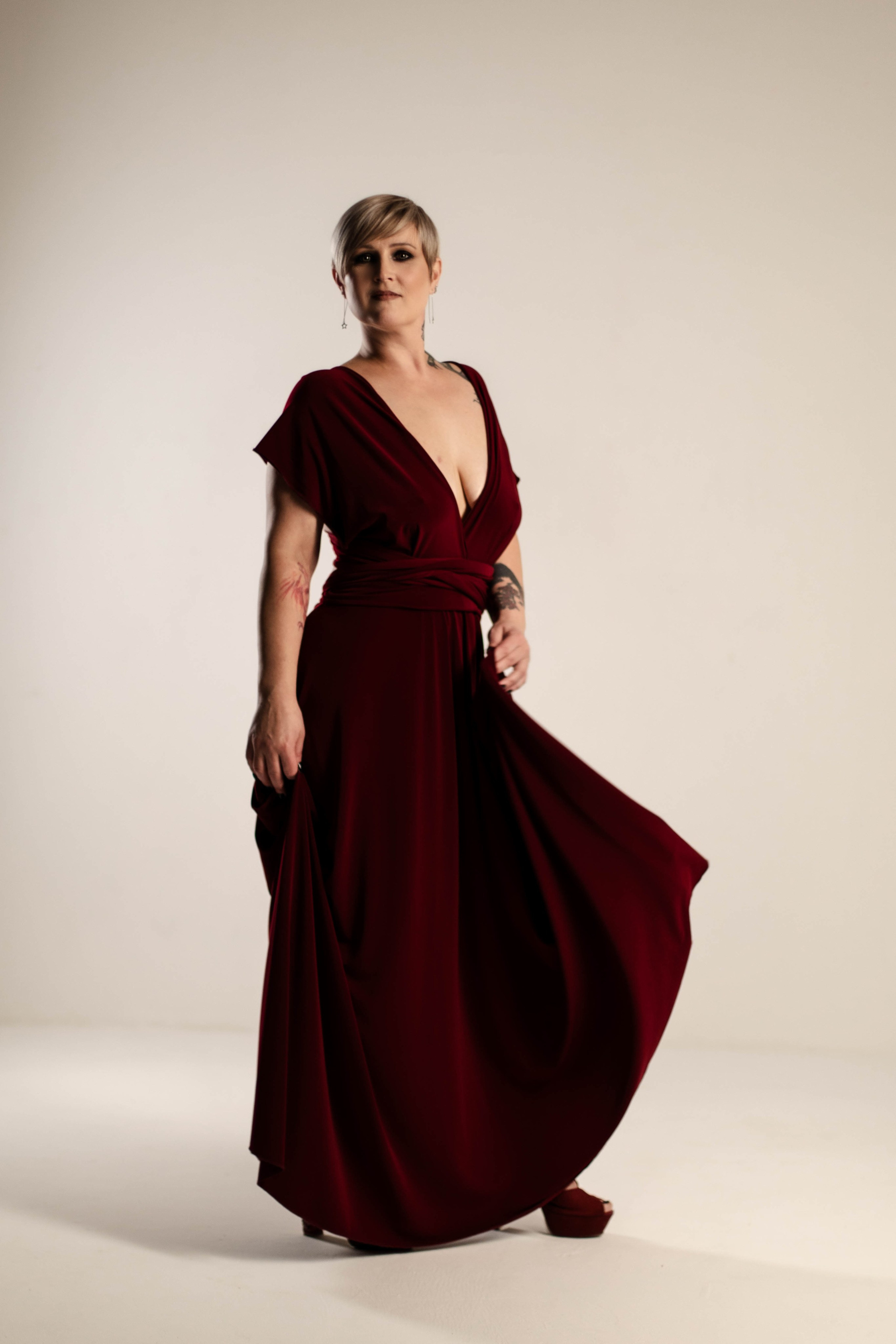 Будуарная фотосессия, девушка в длинном бордовом платье танцует 